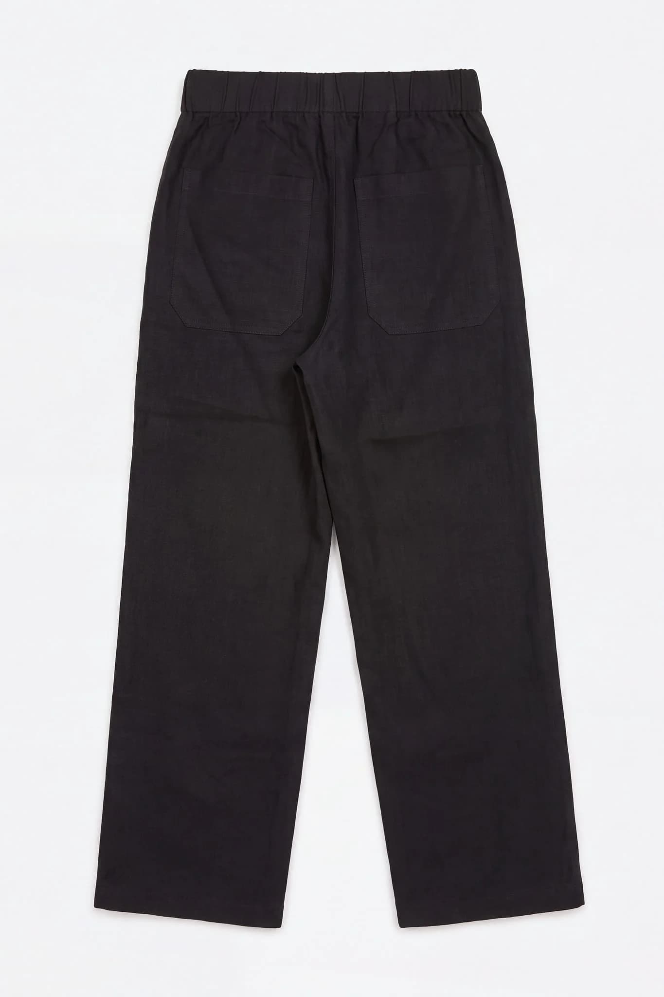 Pantalon large en lin noir à plat, vu de dos, poches plaquées visibles