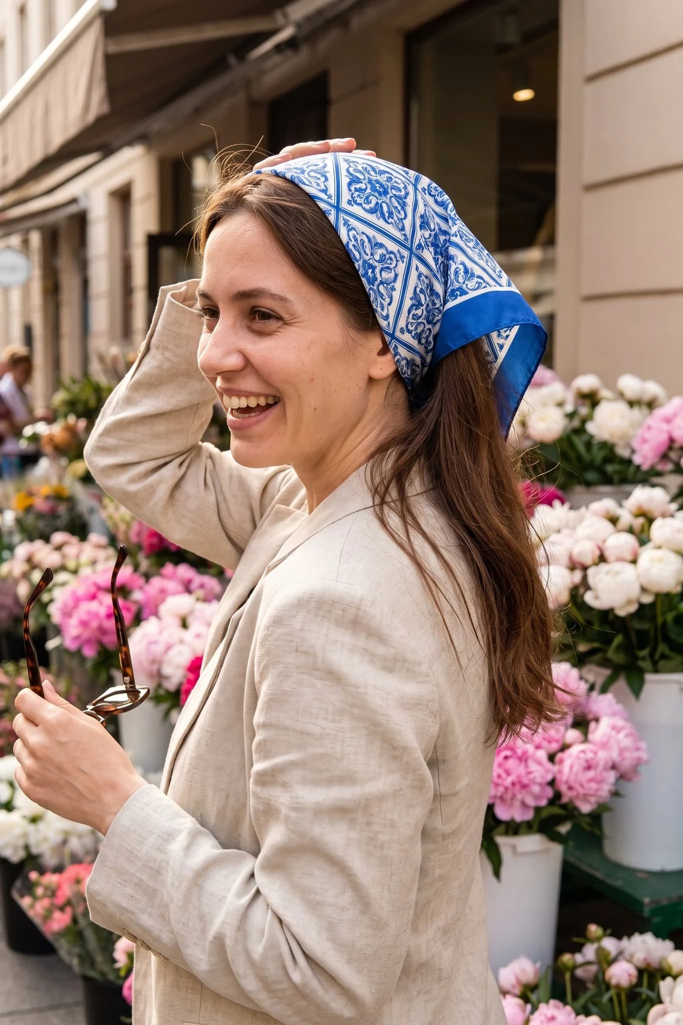 Woman wearing the silk scarf Camaïeu de porcelaine as a bandana in her hair on a Paris street