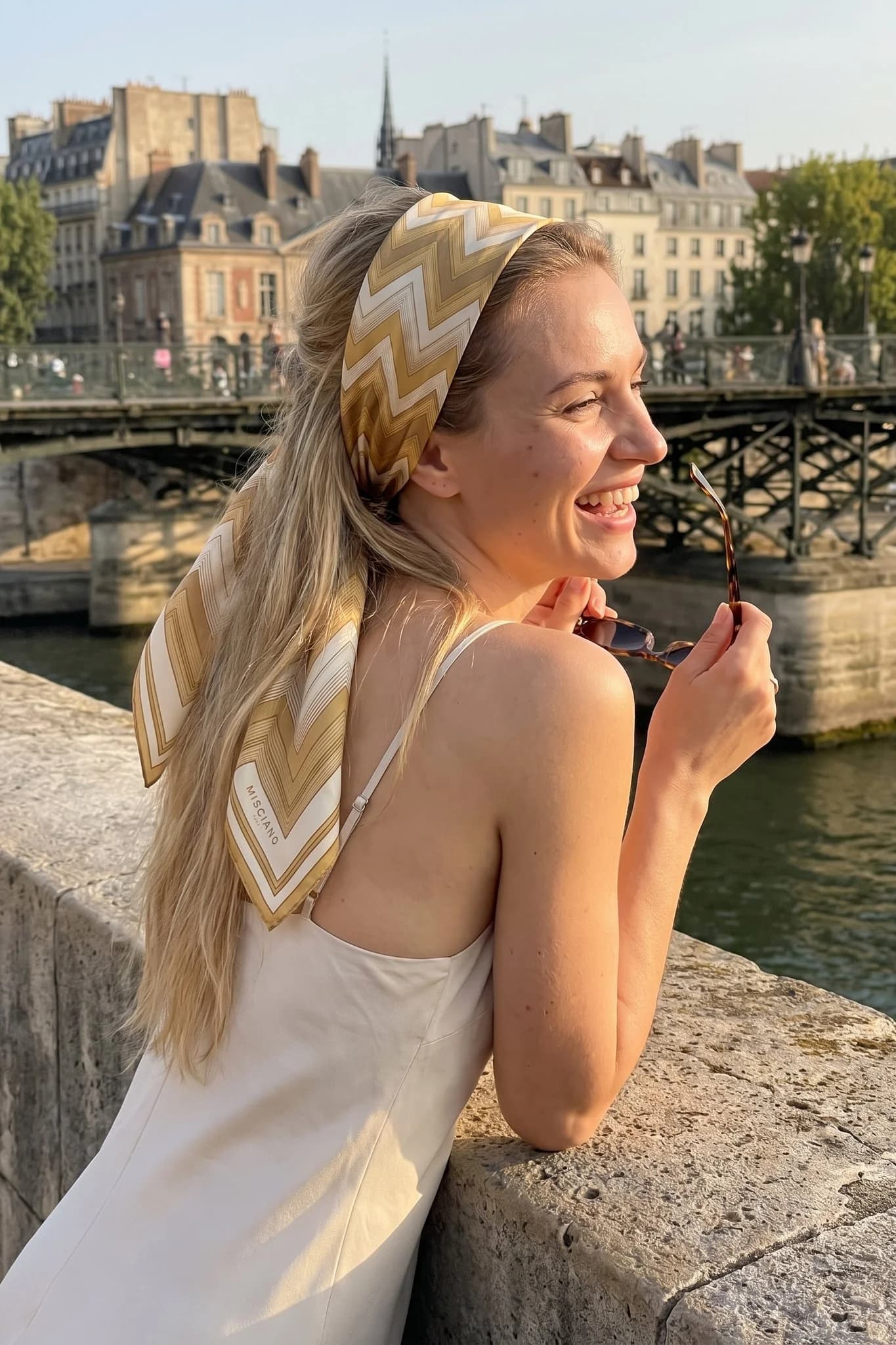 Frau trägt das Seidentuch Chevrons d'or als Bandana im Haar auf einer Straße in Paris