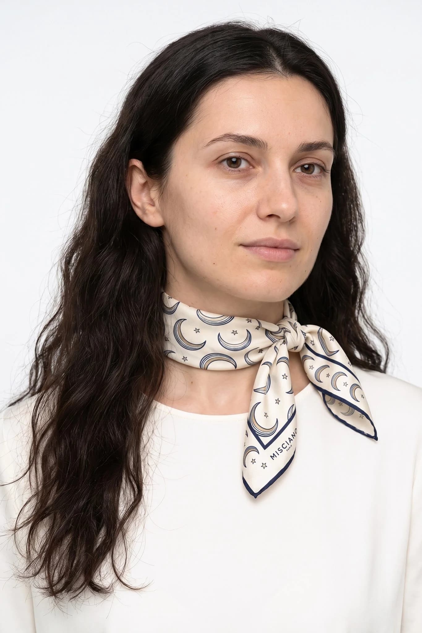 Small silk scarf 50 Croissants de lune worn tied around the neck as a small scarf by a woman, studio view