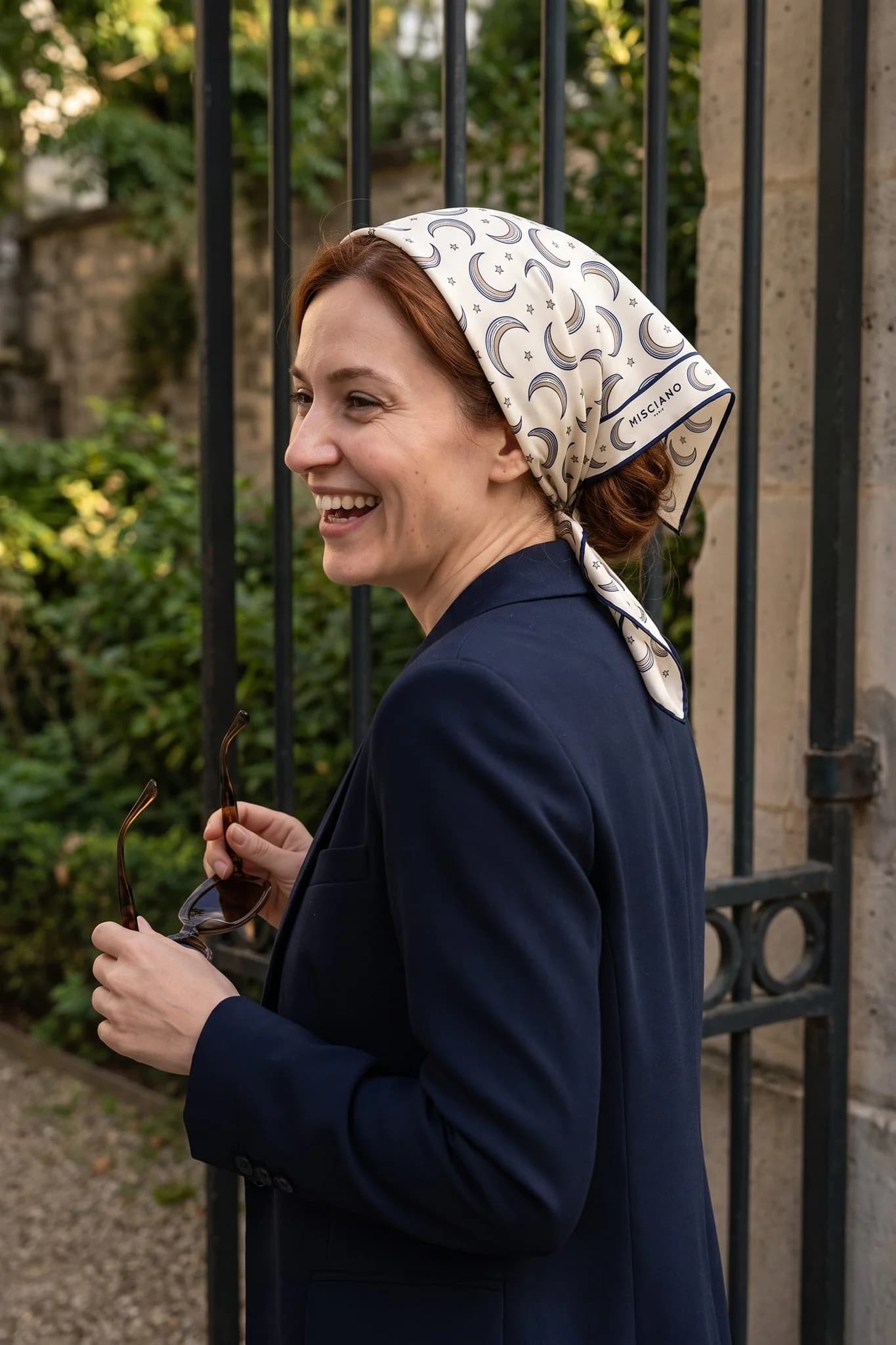 Woman wearing the Croissants de lune silk scarf as a bandana in her hair on a Paris street