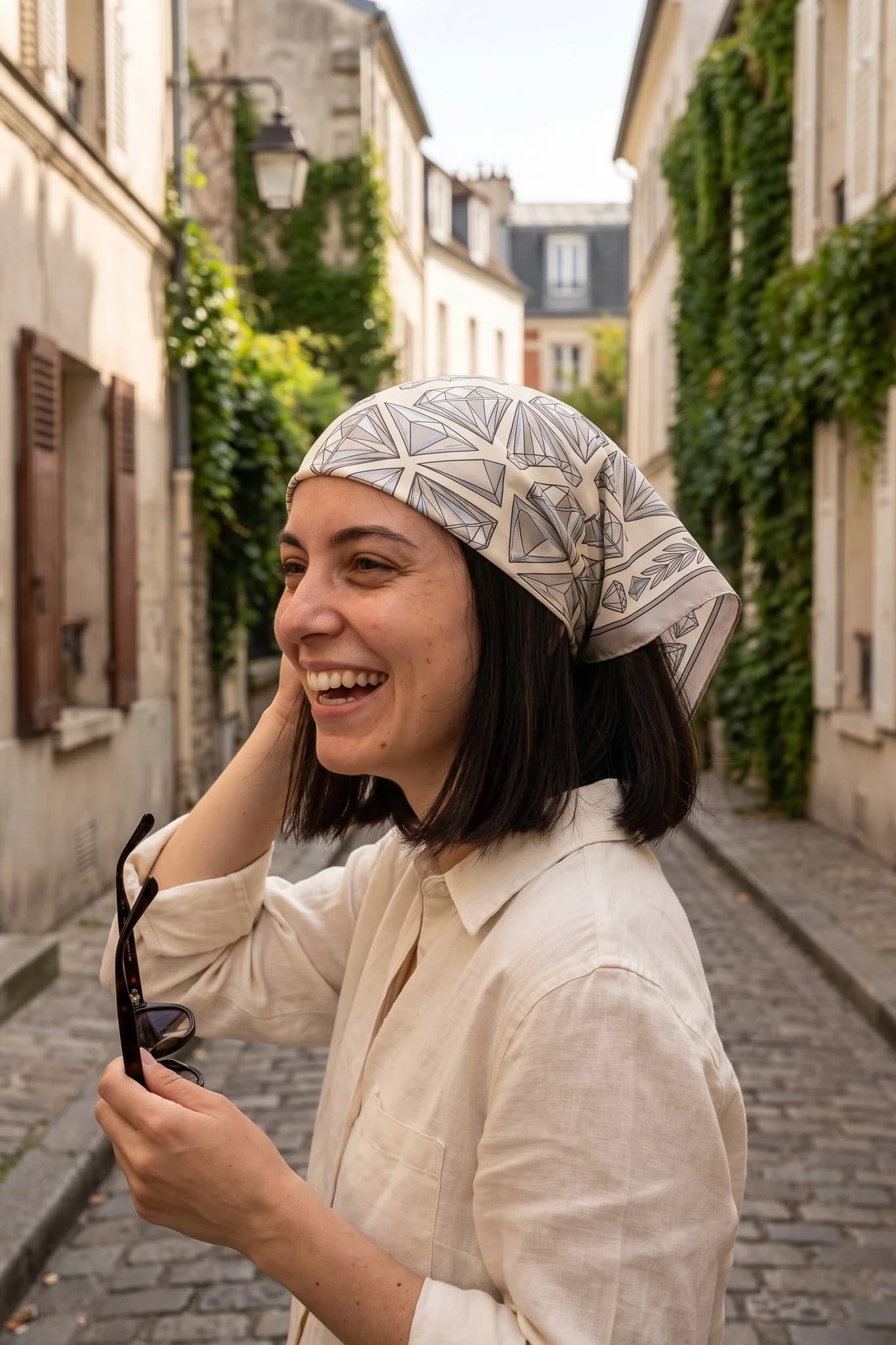 Frau trägt das Seidentuch Diamantsplitter als Bandana im Haar auf einer Straße in Paris