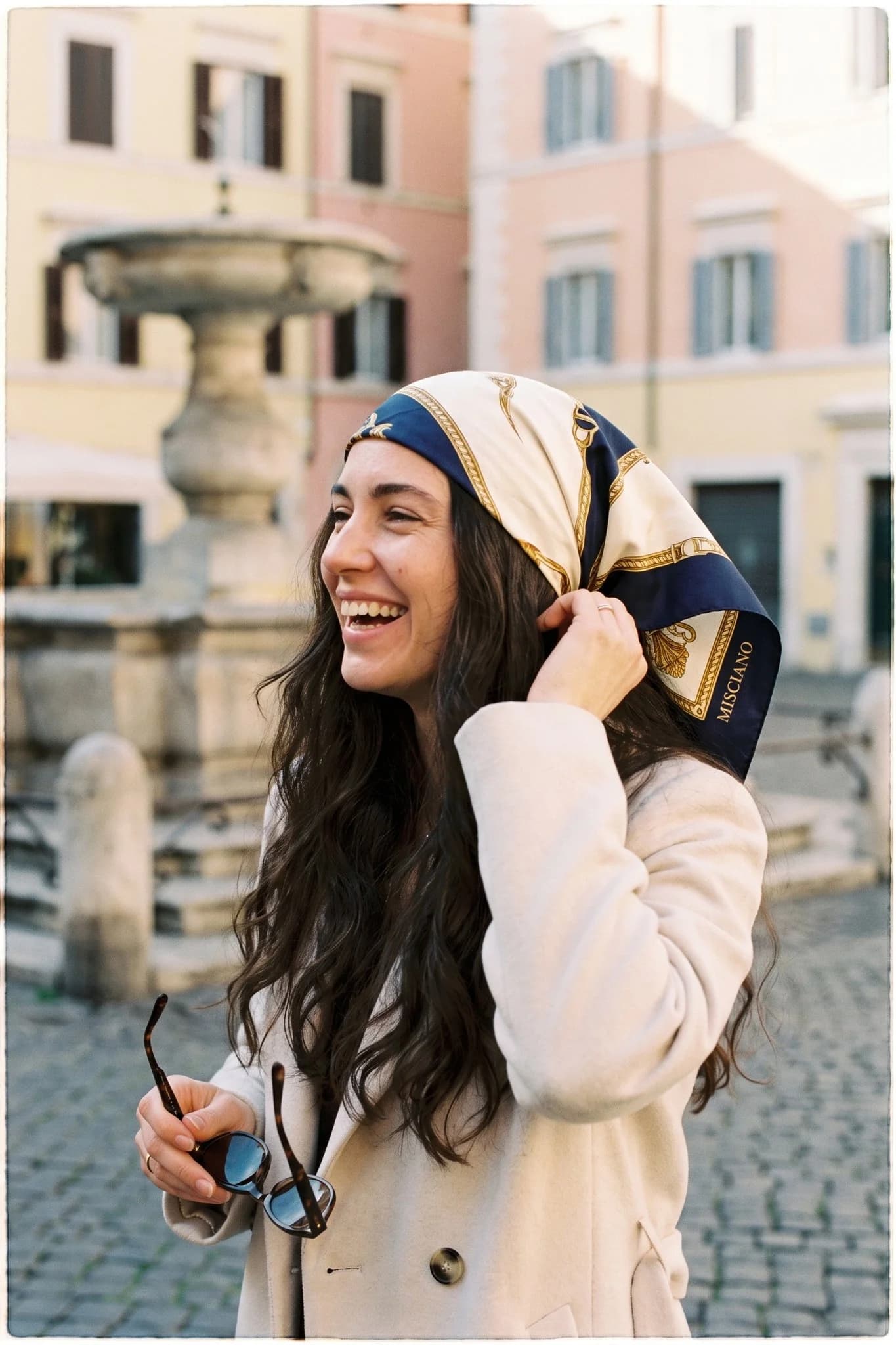 Donna che indossa il fazzoletto di seta Étoile du berger come bandana nei capelli in una strada di Parigi