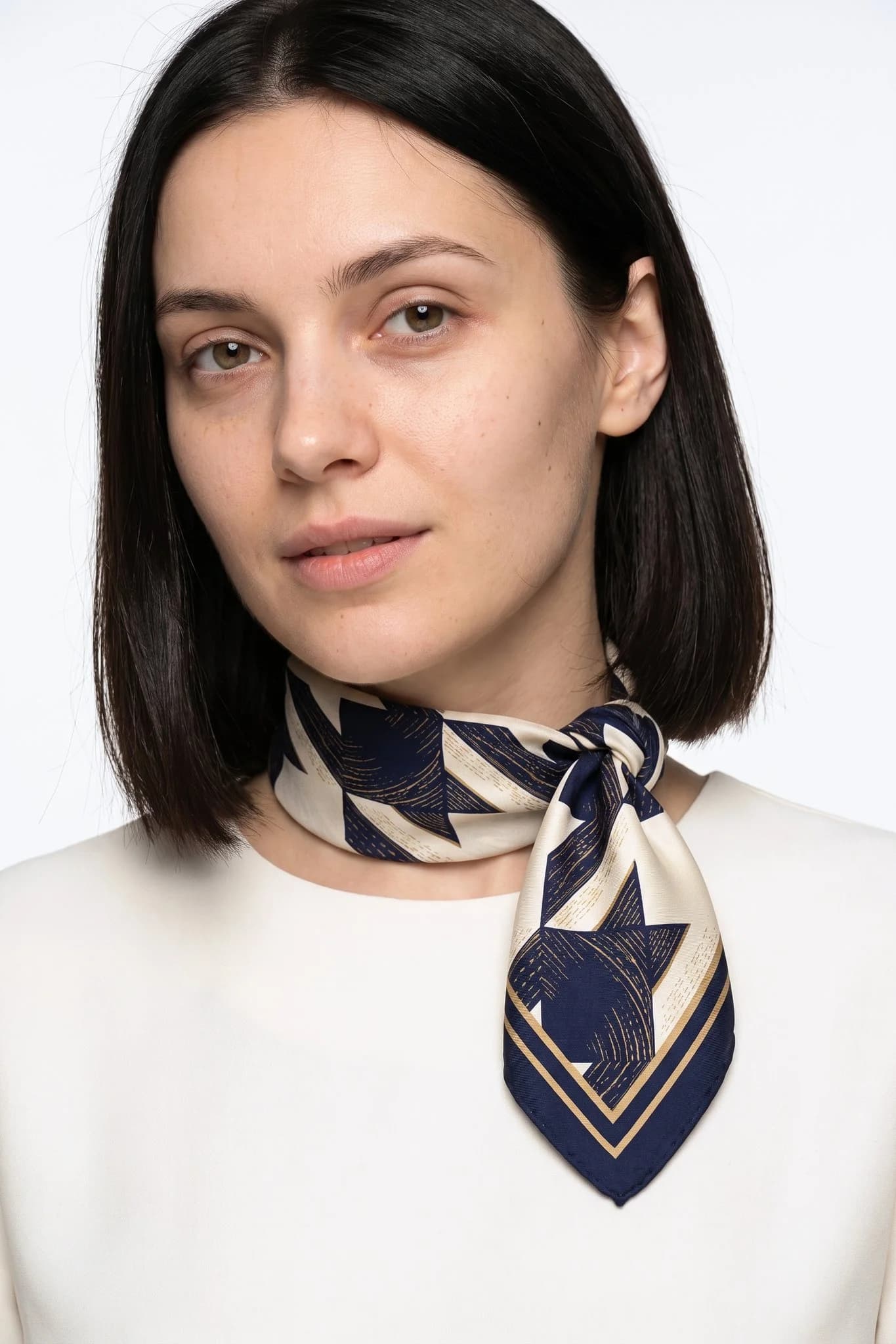 Small 50 silk square Parisian houndstooth worn tied around the neck as a small scarf by a woman, studio view