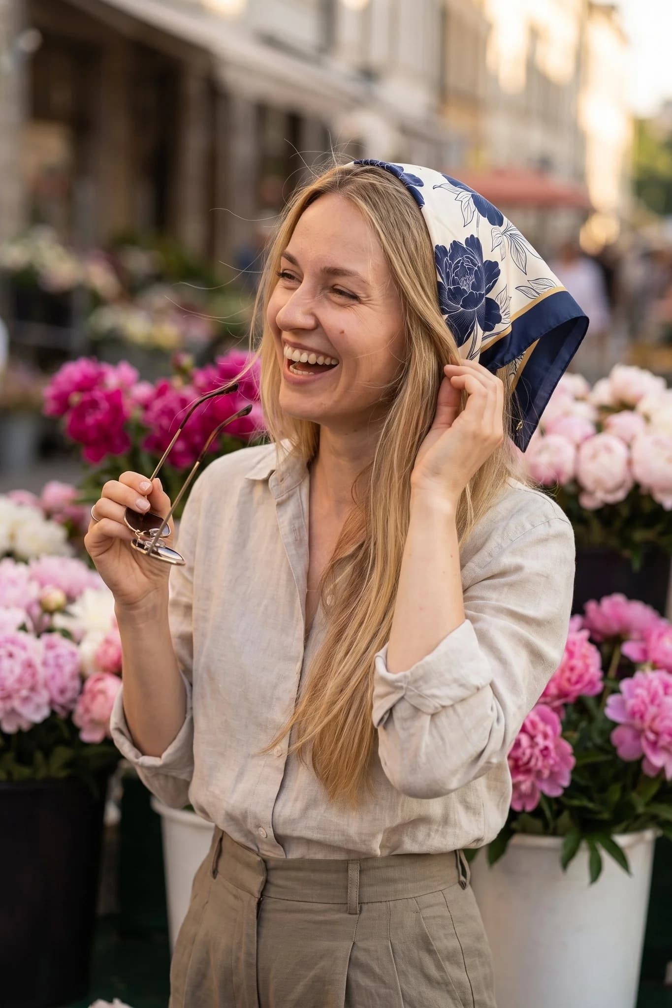 Женщина носит шелковый платок Pivoines d'encre как бандану в волосах на улице Парижа
