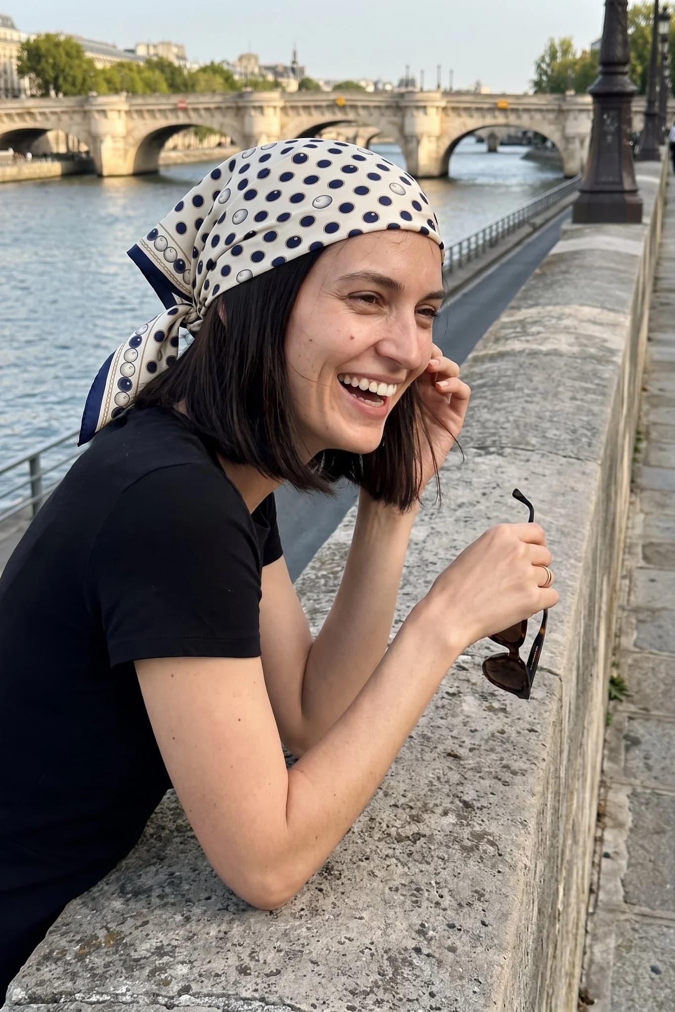 Frau trägt das Seidentuch Pois et perles als Bandana im Haar auf einer Straße in Paris