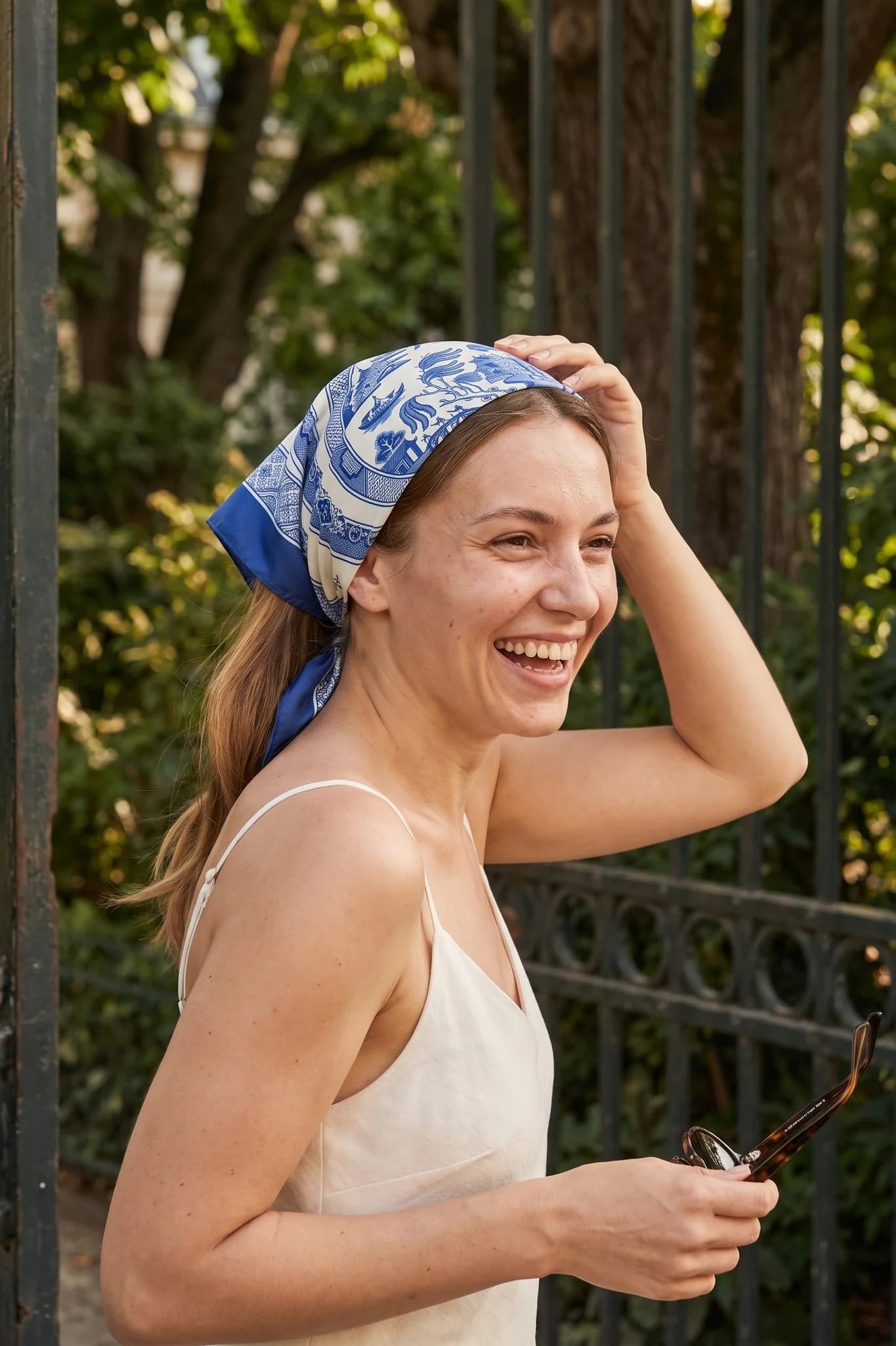 Frau trägt das Seidentuch Blaues Porzellan als Bandana im Haar auf einer Straße in Paris