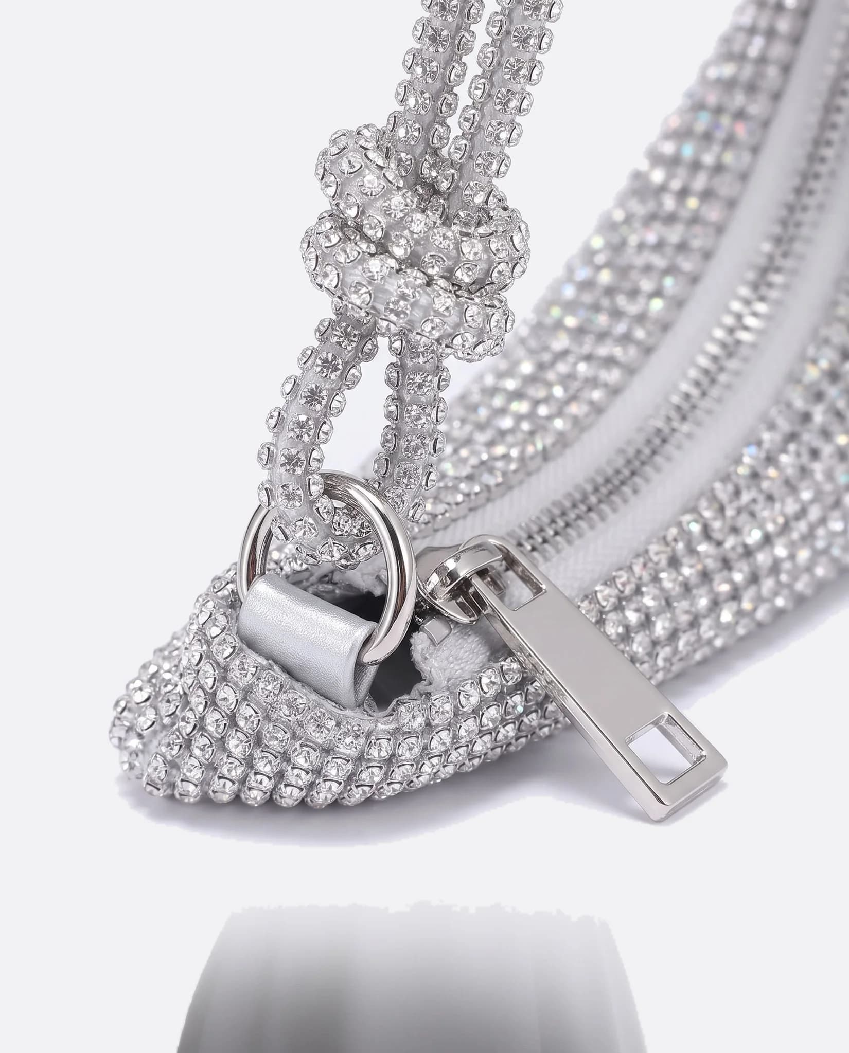 Primo piano del manico annodato e della chiusura argentata della pochette in strass