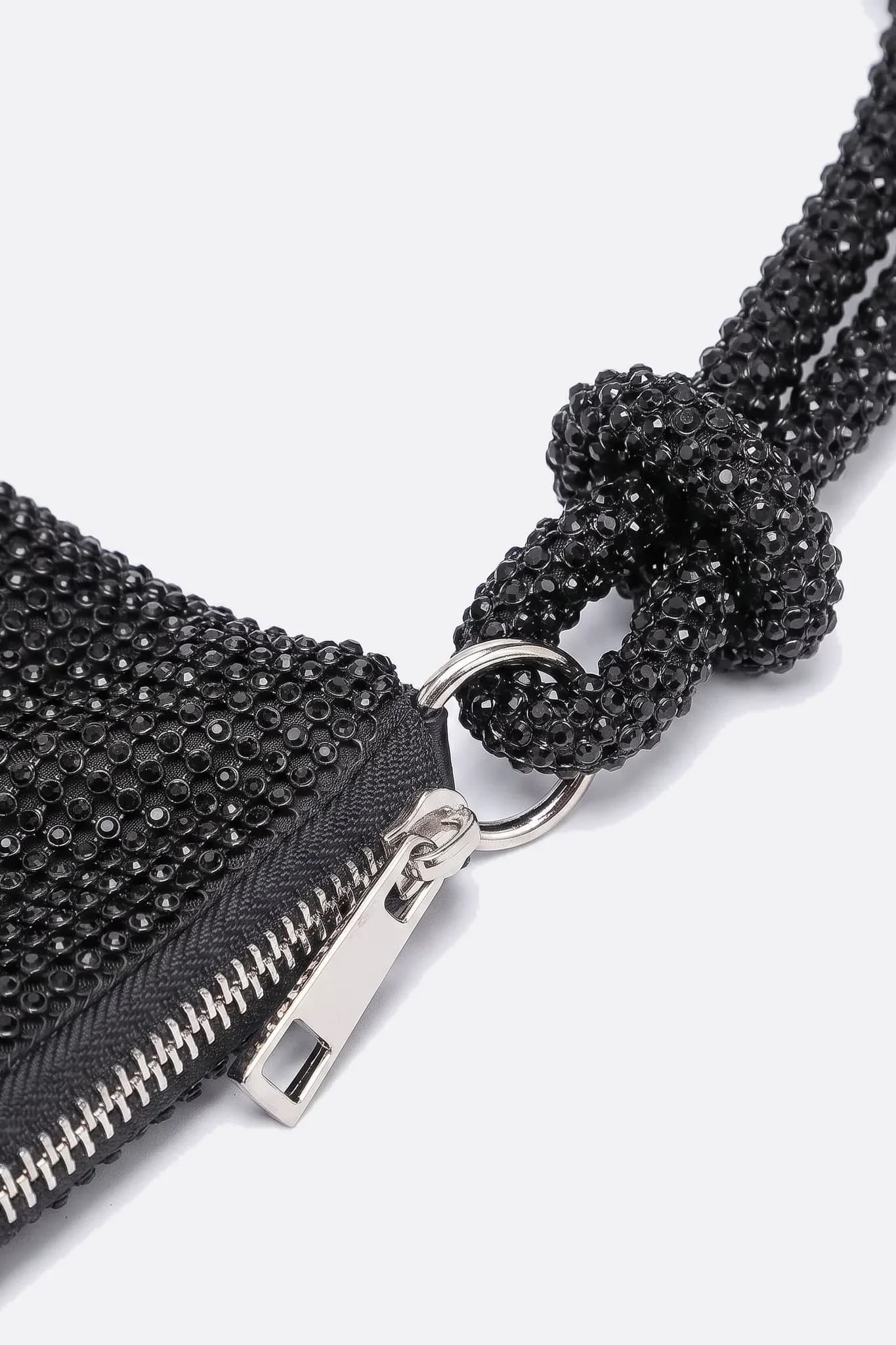 Primo piano del manico annodato e della chiusura argentata della pochette in strass nero