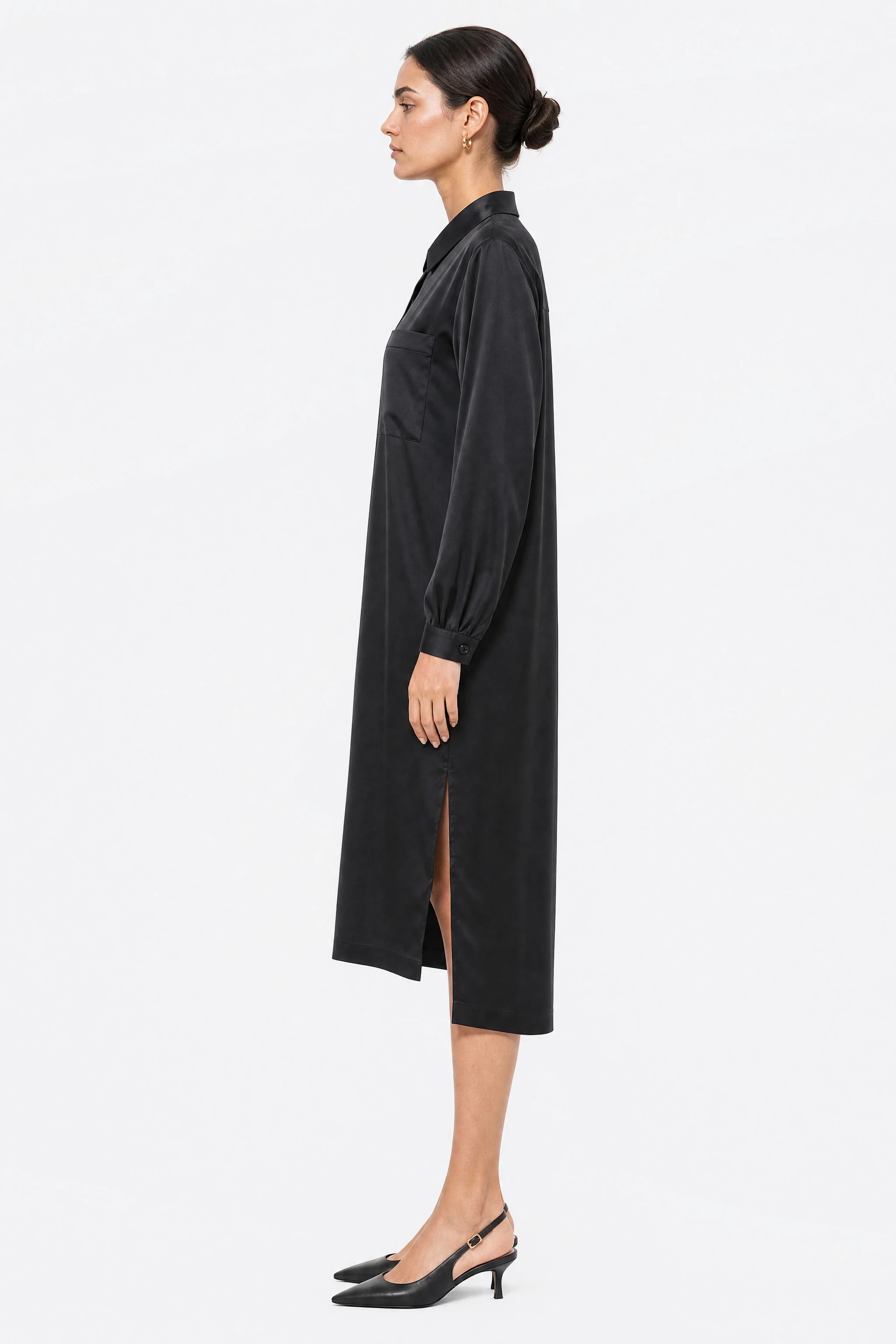 Robe chemise longue en satin noir vue de profil, tombé fluide et fente latérale