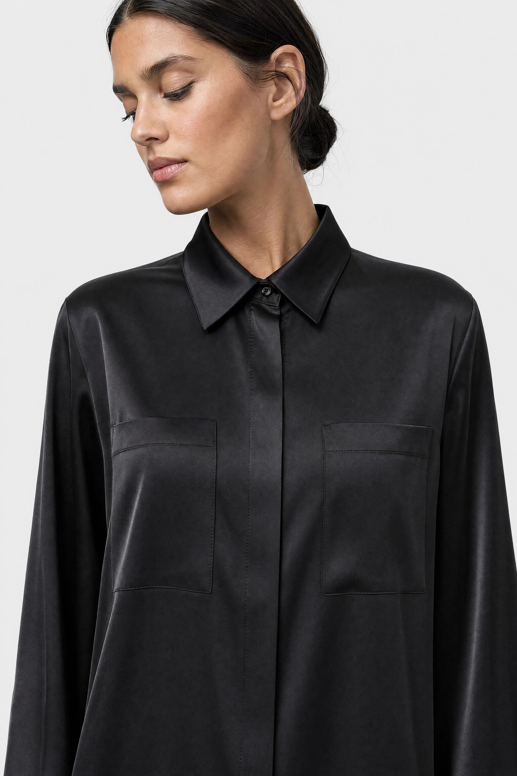 Détail du poignet boutonné et de la poche latérale de la robe chemise en satin noir