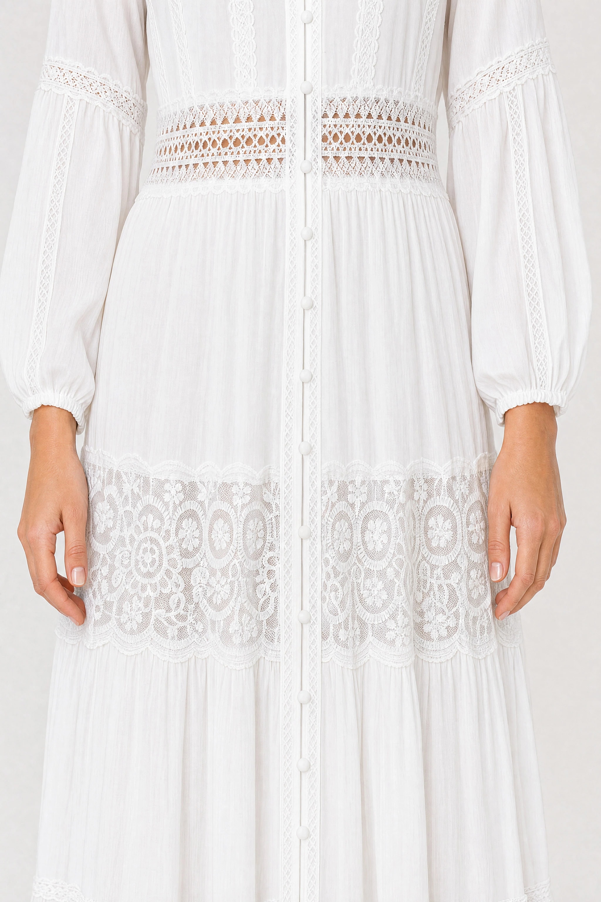 Nahaufnahme des besticktem Tulle-Streifens mit floralen Medaillons und der Volants des weißen Maxikleids