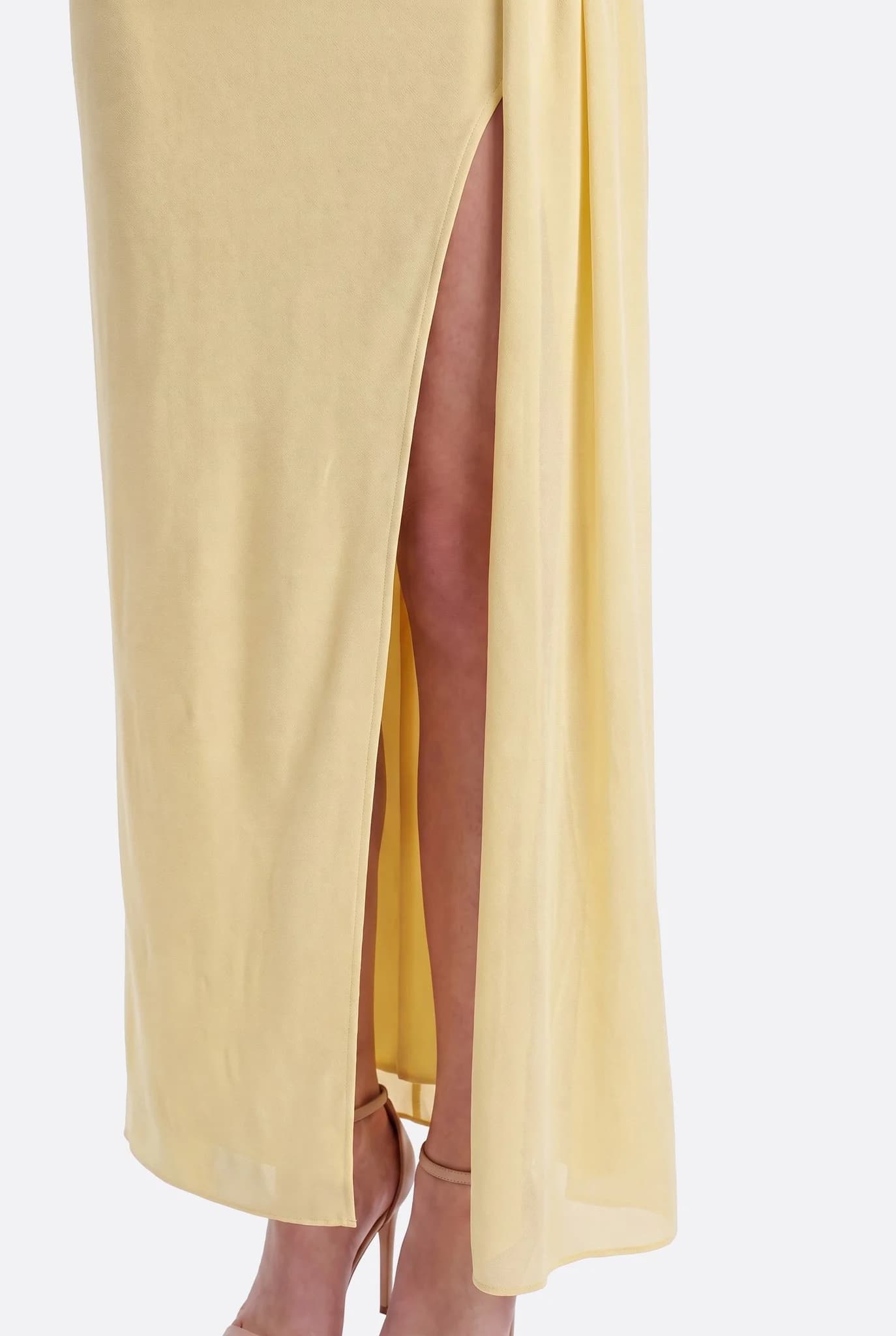 Primer plano de la abertura frontal del vestido largo amarillo pastel, pierna al descubierto hasta la mitad del muslo