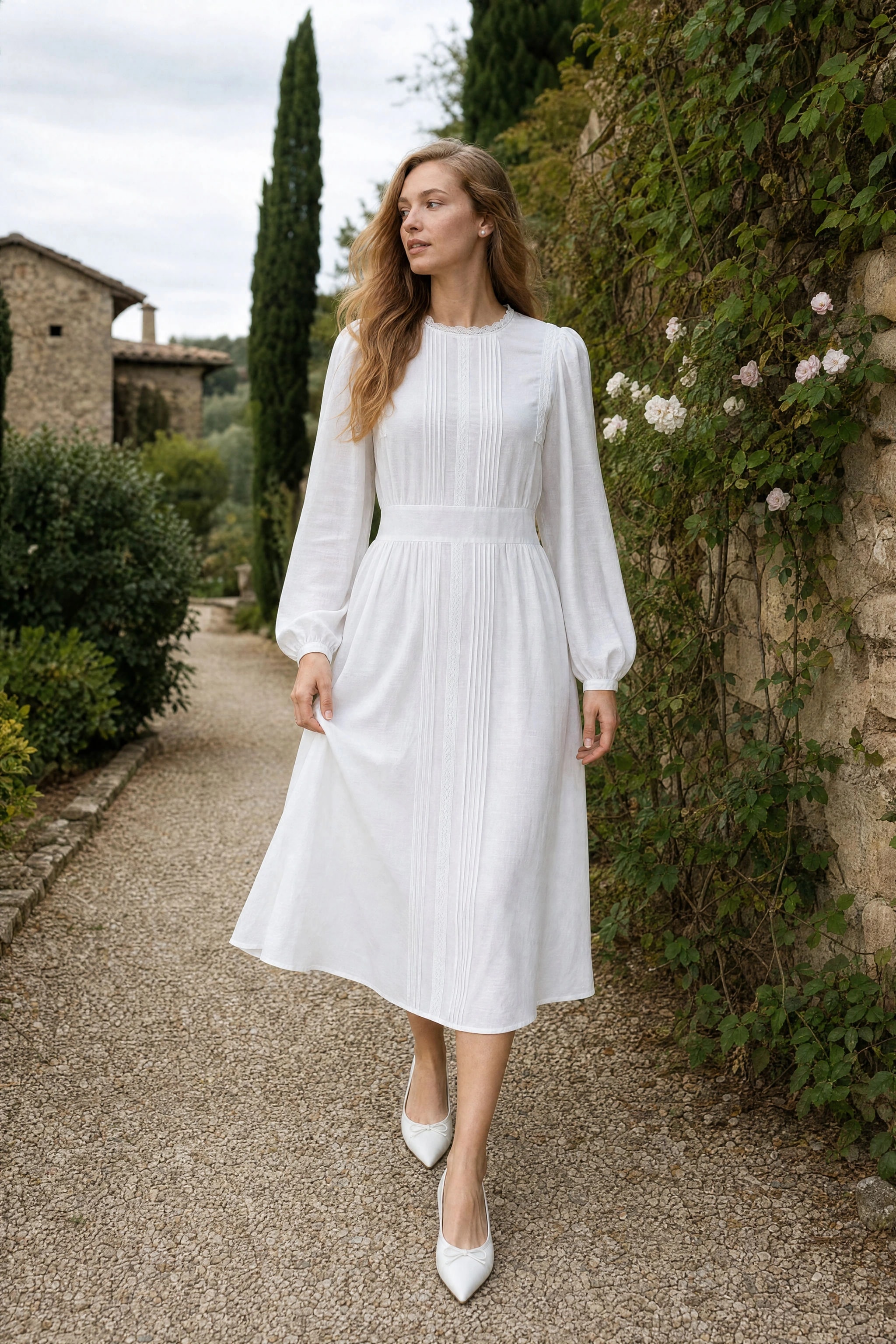 Weißes Midikleid mit Biesen, getragen im Garten eines toskanischen Bauernhofs