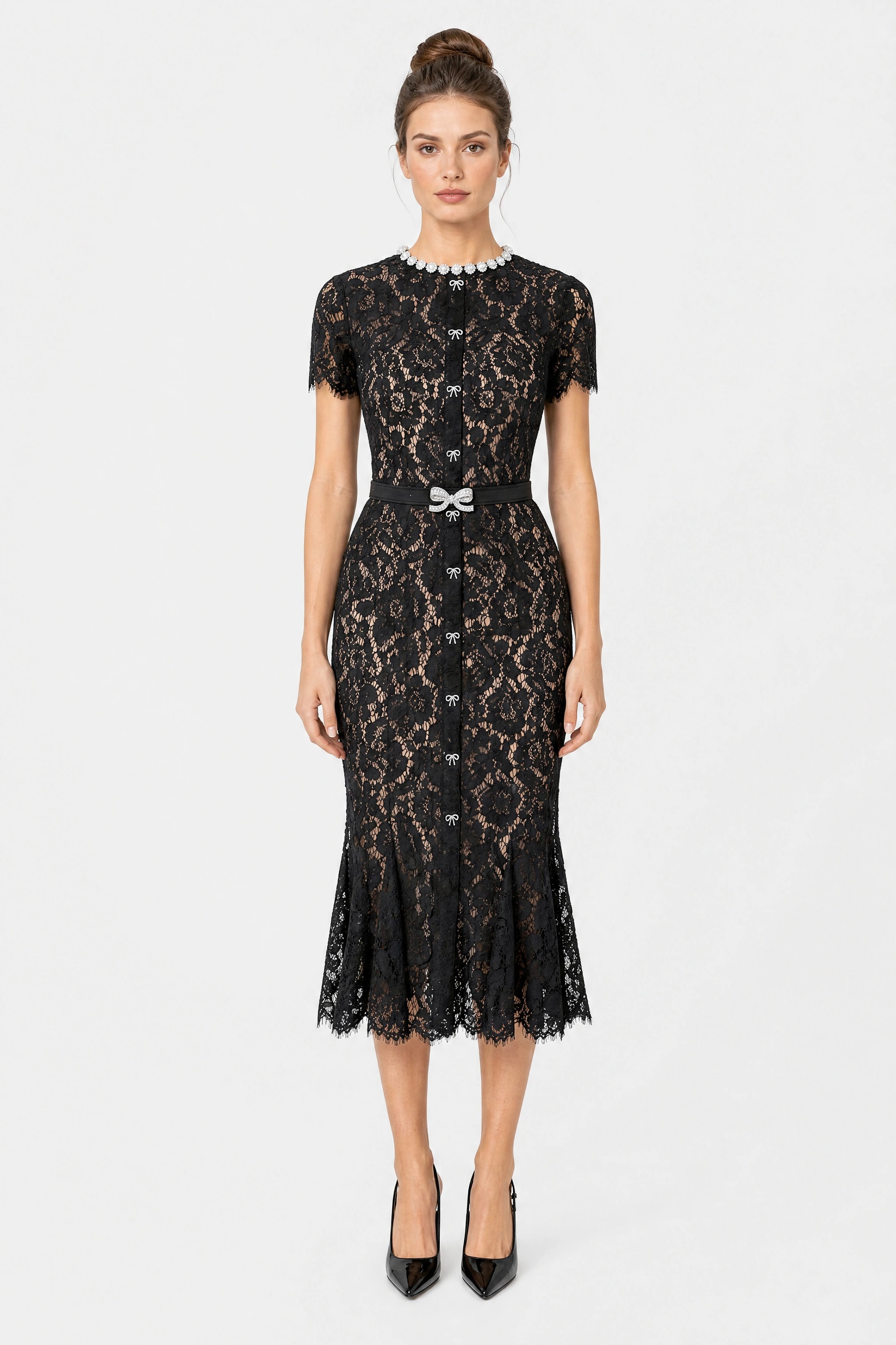 Vestito midi in dentelle cordonnée nera Misciano indossato di fronte, fodera color carne, colletto di perle, patта centrale con fiocchi in strass e cintura