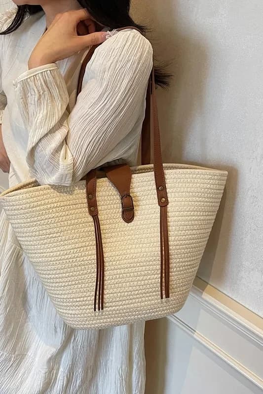 Sac cabas tressé effet paille blanc crème porté à l’épaule avec une robe blanche