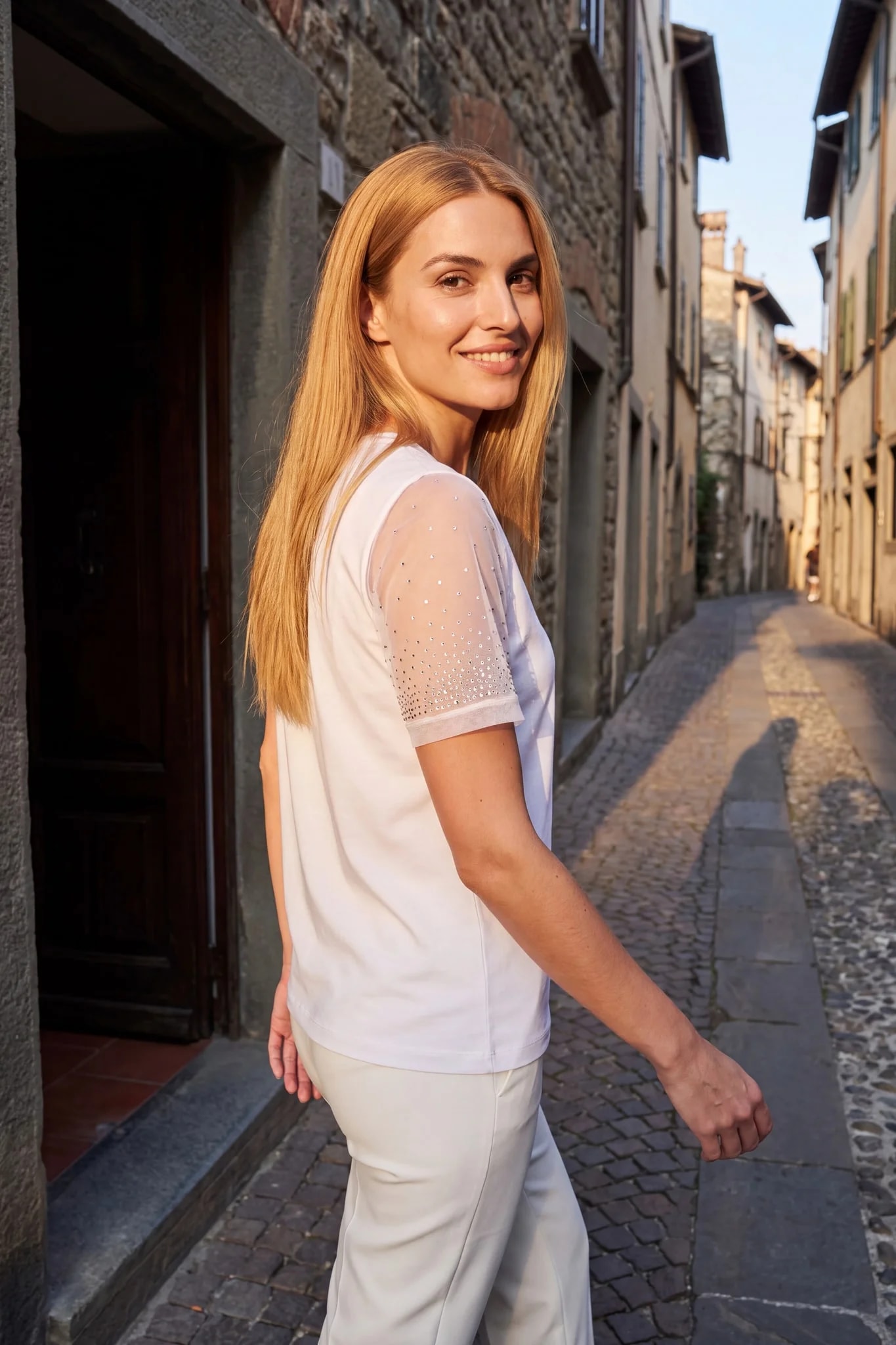 T-shirt blanc à manches strassées porté dans une rue italienne ensoleillée