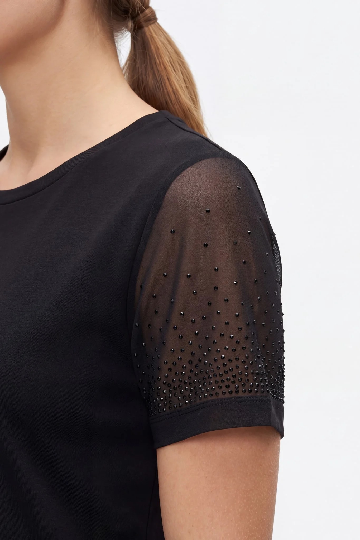 Détail de la manche en voile noir transparent semée de strass de plus en plus denses