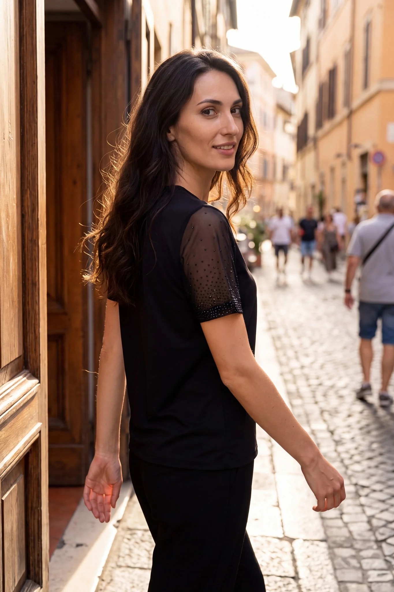 T-shirt noir à manches strassées porté dans une rue italienne en début de soirée