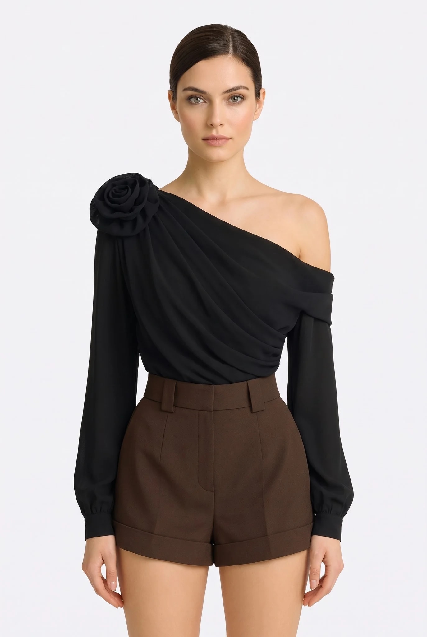 Front-facing model wearing the black asymmetric draped top with sculpted flower, bare shoulder and long sleeves