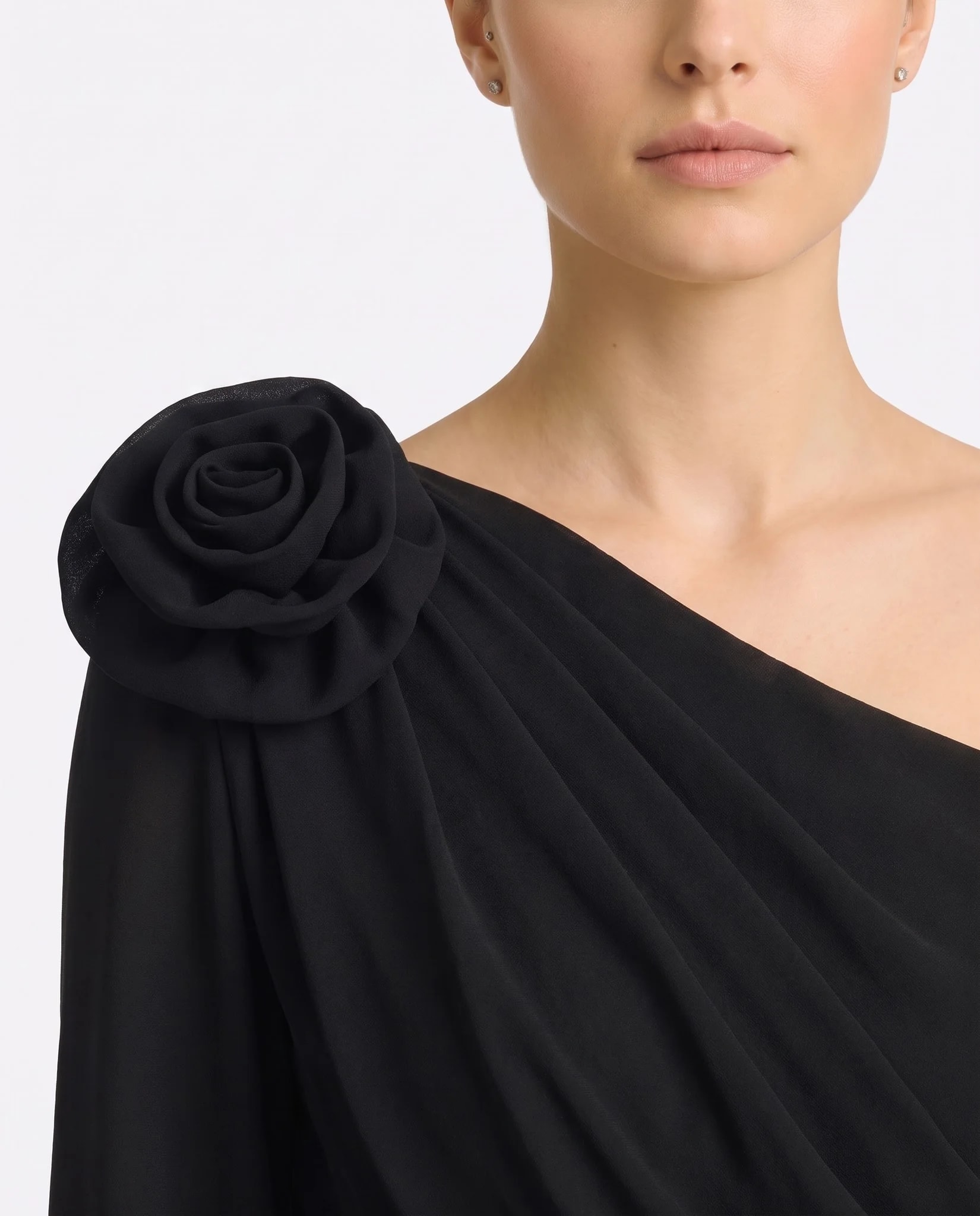 Close-up on the sculpted flower in opaque black crepe and the gathers of the shoulder drape