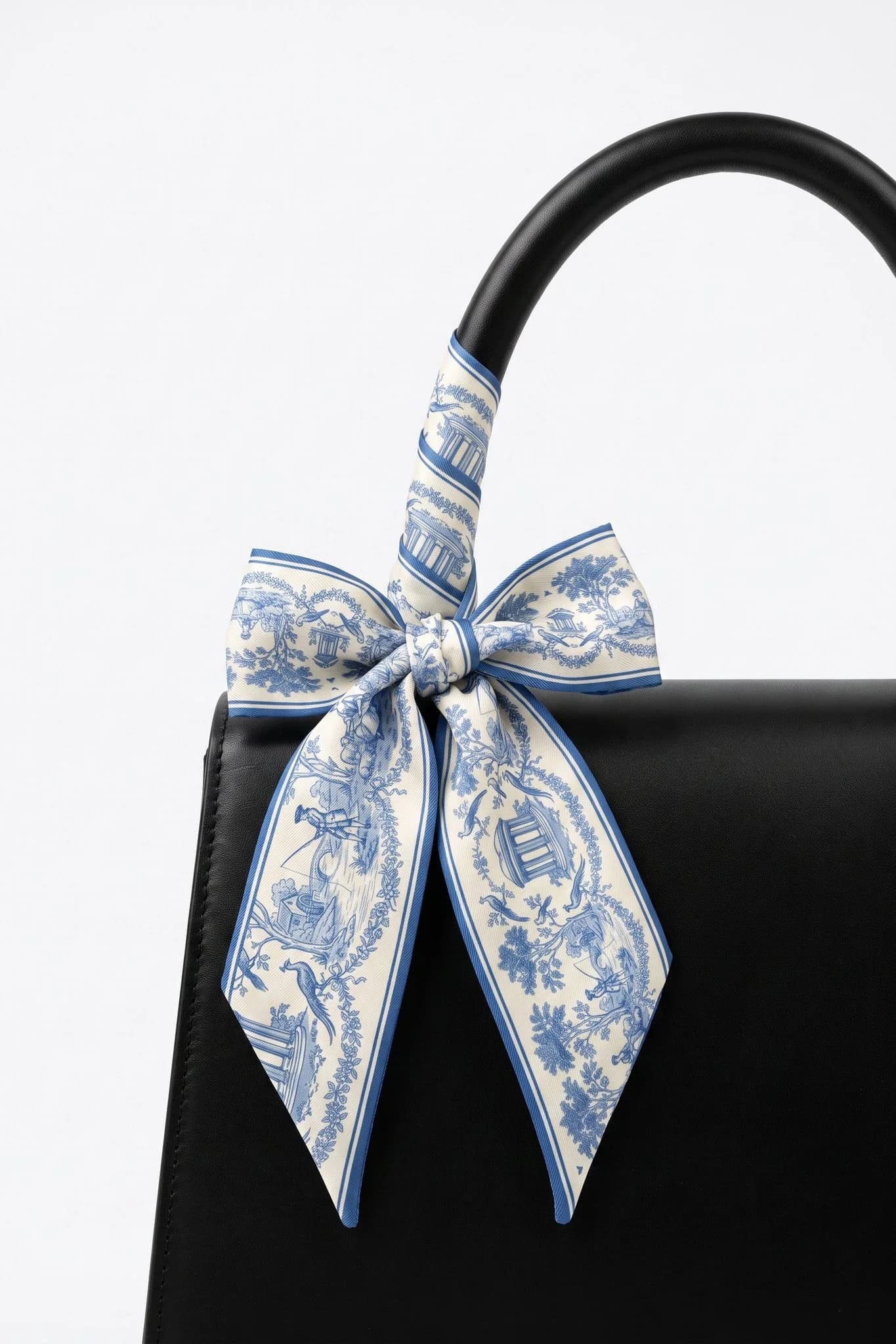 Twilly Toile de rêverie enroulé et noué autour de l'anse d'un sac en cuir noir