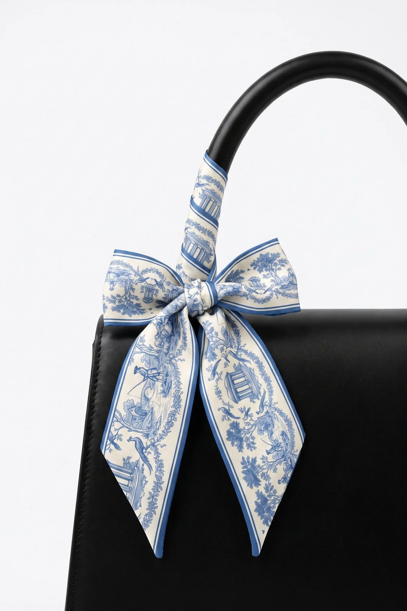 Toile de rêverie twilly rolled and tied around the handle of a black leather bag
