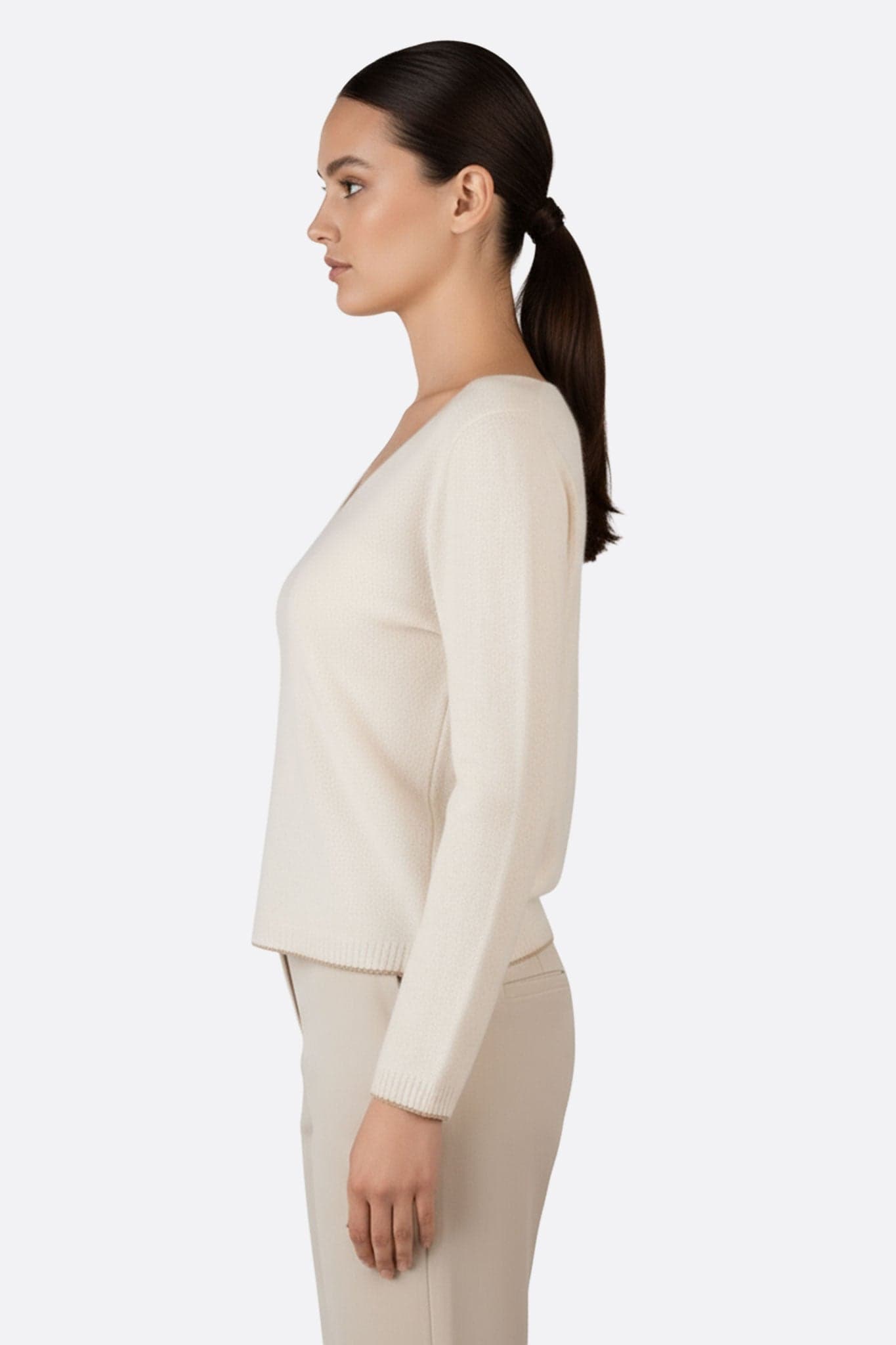Détail du pull beige en laine mérinos et cachemire avec col V et délicates finitions dorées, parfait pour le chic quotidien.
