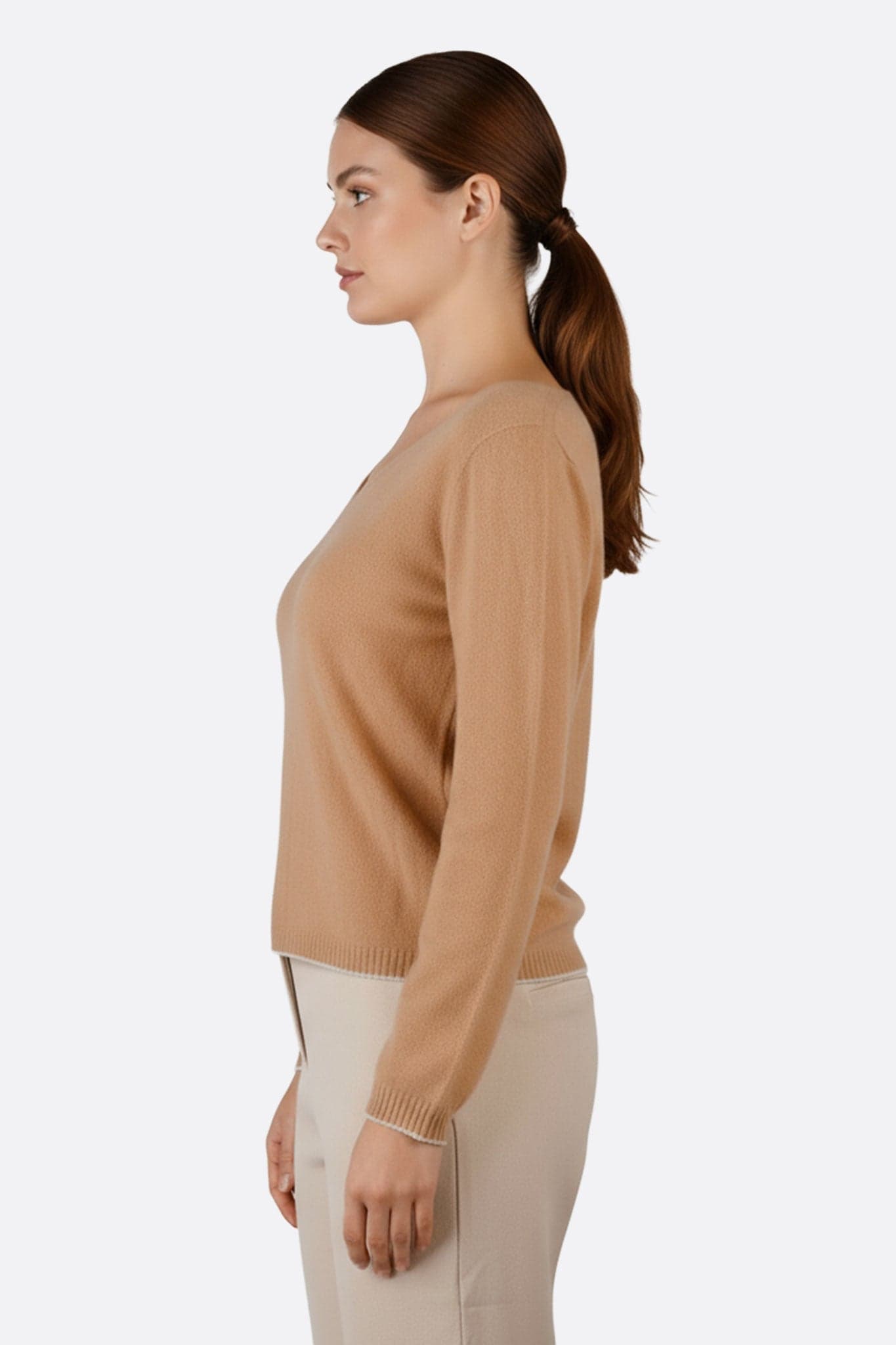 Détail raffiné d'un pull beige en laine mérinos et cachemire, mettant en avant son col V et ses finitions grises contrastées.