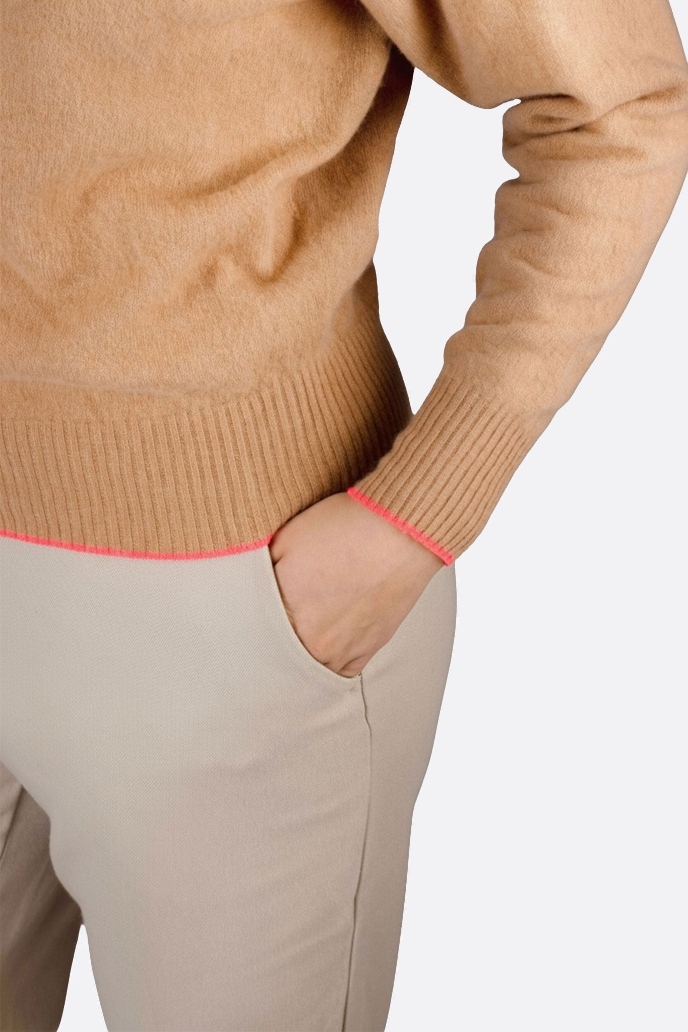 Dettaglio del maglione beige in lana merino e cashmere, mettendo in evidenza i bordi rosa fluo per un tocco elegante.