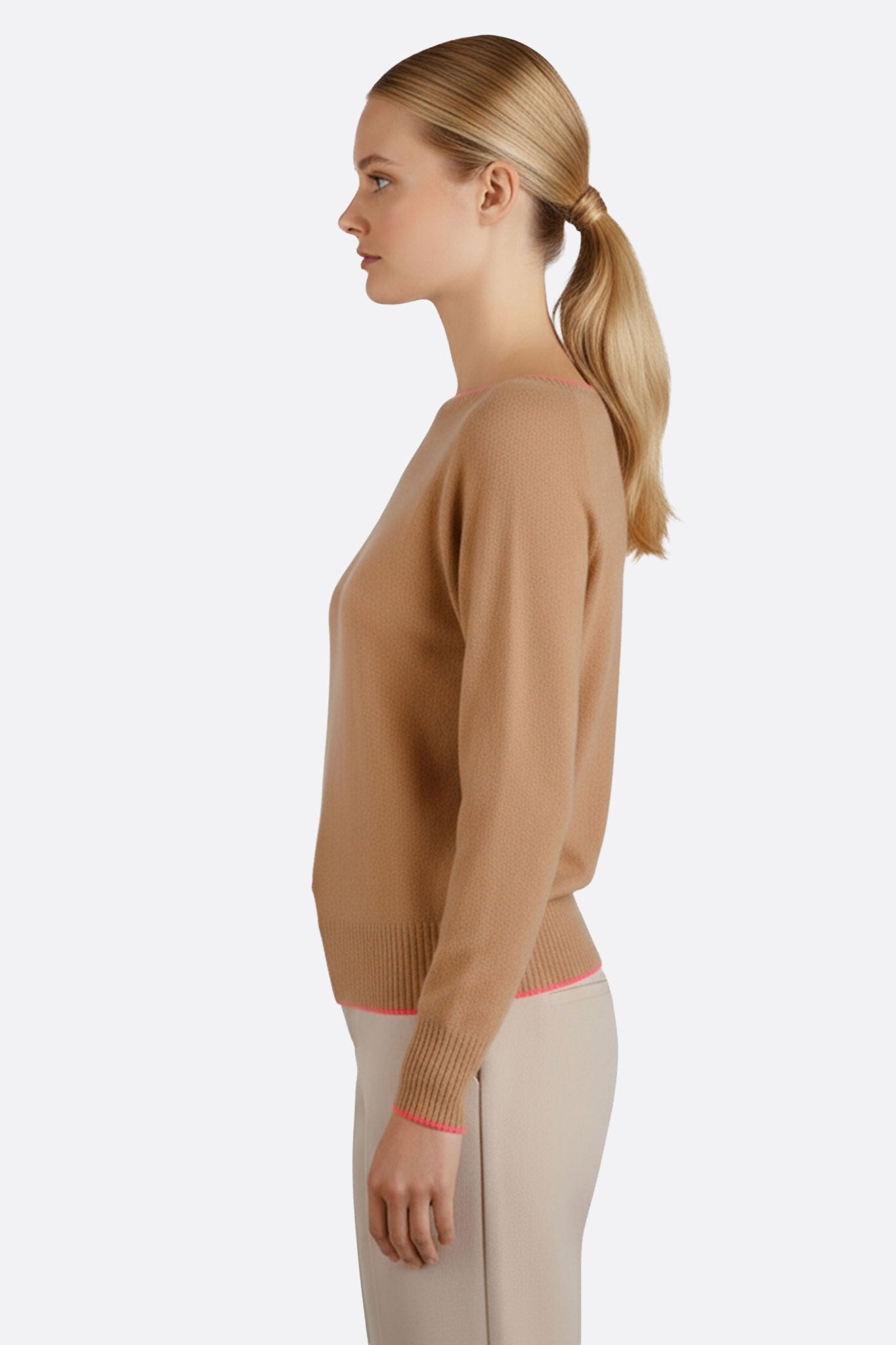 Primo piano su un maglione beige in lana merino, cashmere morbido, con eleganti bordi rosa fluo, ideale per una serata raffinata.