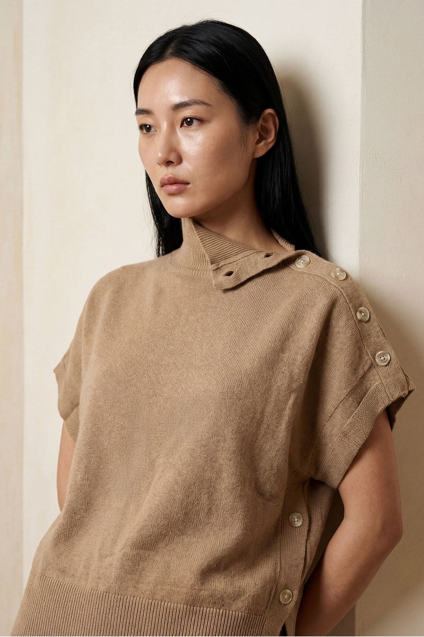 Detail of the snap sides of the beige poncho sweater, an elegant choice for a comfortable and stylish everyday outfit.