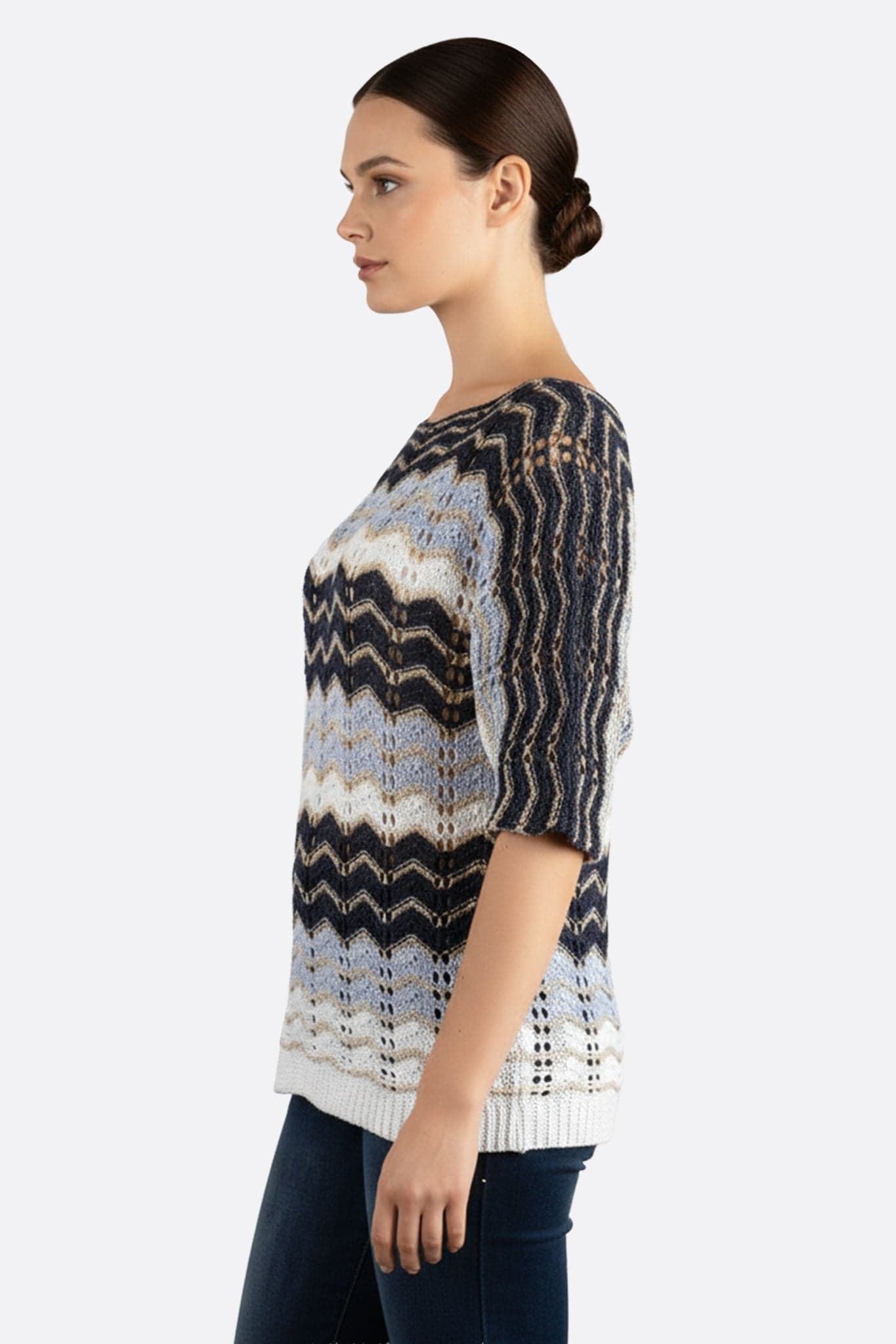 Nahaufnahme des Pullovers aus blauer und weißer Lochstickerei, elegantes Chevron-Muster, ideal für einen raffinierten Alltagsstil.
