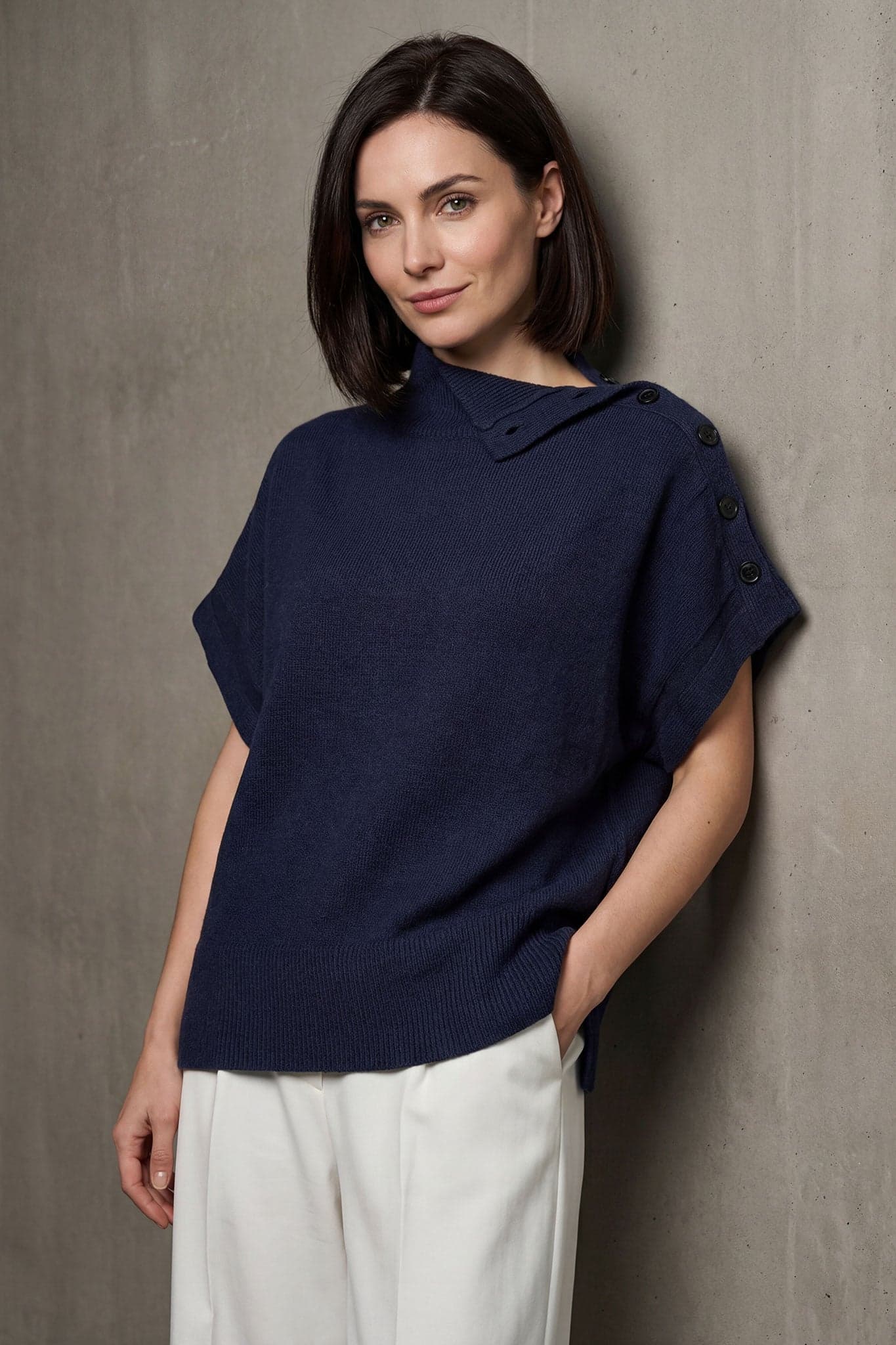 Detail of the oversized navy blue sweater with stand-up collar, decorative buttons and snap sides for a chic touch.