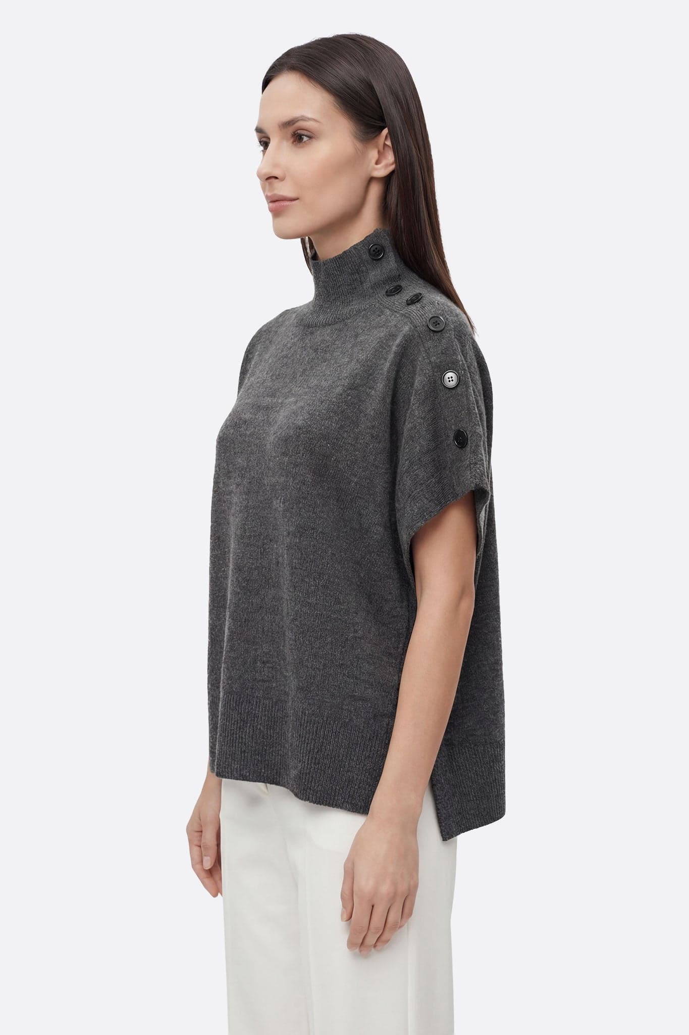 Primo piano del collo alto abbottonato del poncho maglione grigio, che offre calore ed eleganza per un'uscita informale.