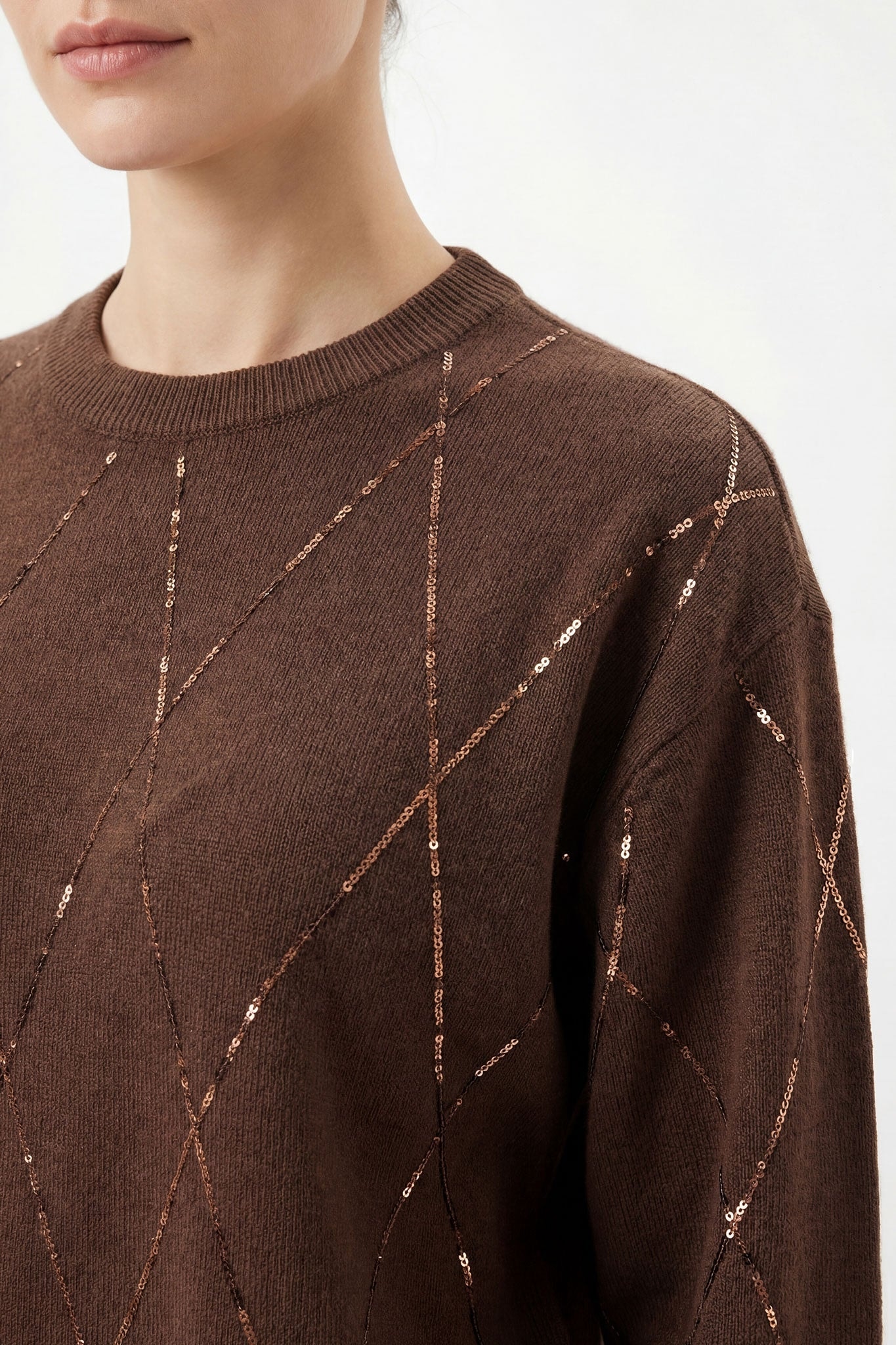 Primo piano di un maglione marrone in lana mista, ornato di scintillii, ideale per una serata elegante o una giornata...