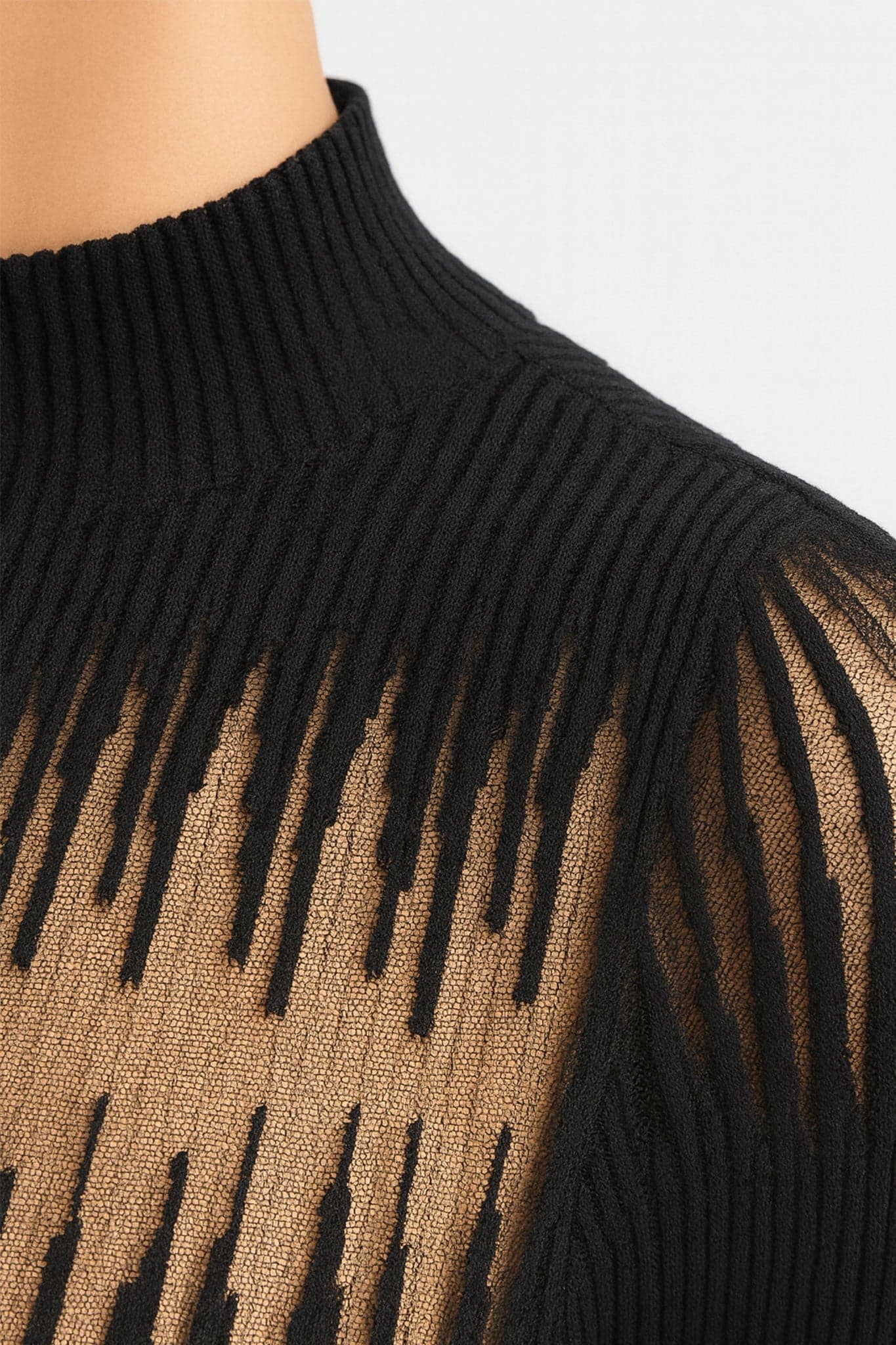 Moderner schwarzer Pullover mit langen Ärmeln und transparentem Nude-Einsatz, perfekt für ein schickes Abendoutfit.