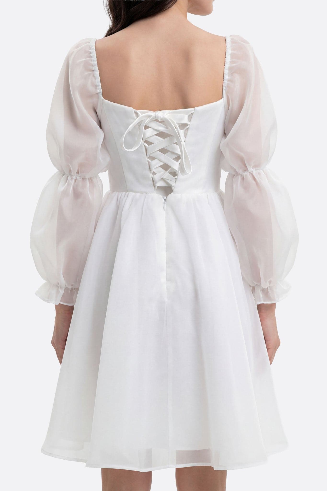 White Lauren short dress with puffed sleeves worn from the back, detail of corset lacing and organza sleeves