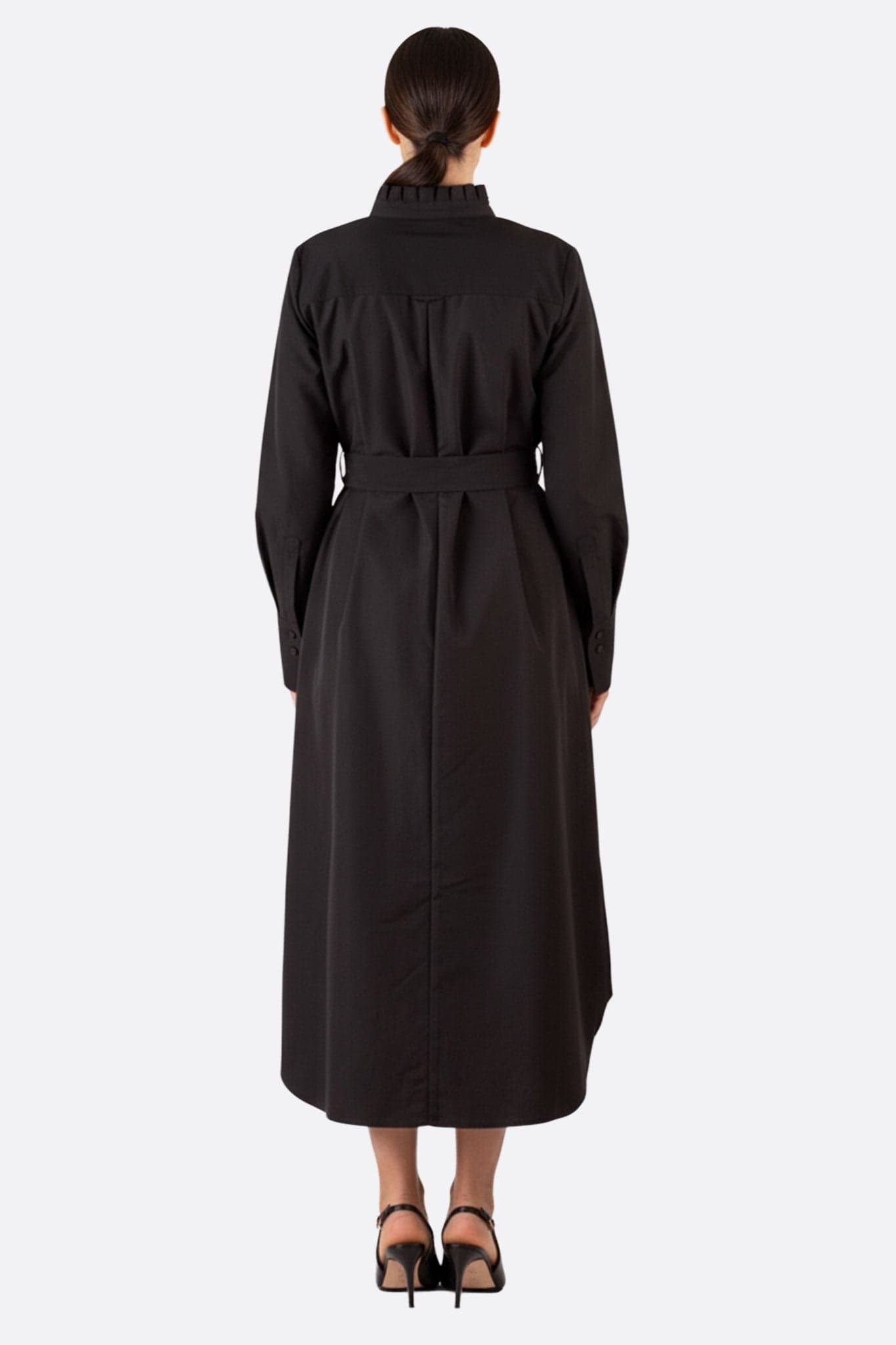 Vista tre quarti dell'abito camicia lungo nero con cintura, che ne sottolinea la silhouette elegante e lo stile contemporaneo.