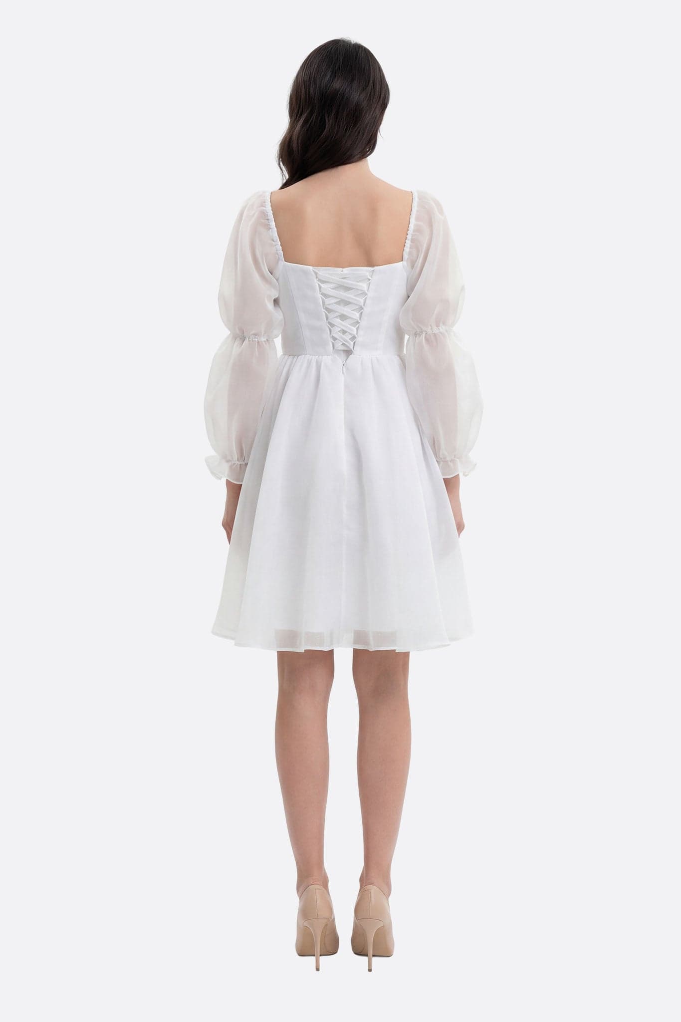 White Lauren short dress worn from the back, with corset lacing and puffed sleeves in sheer organza