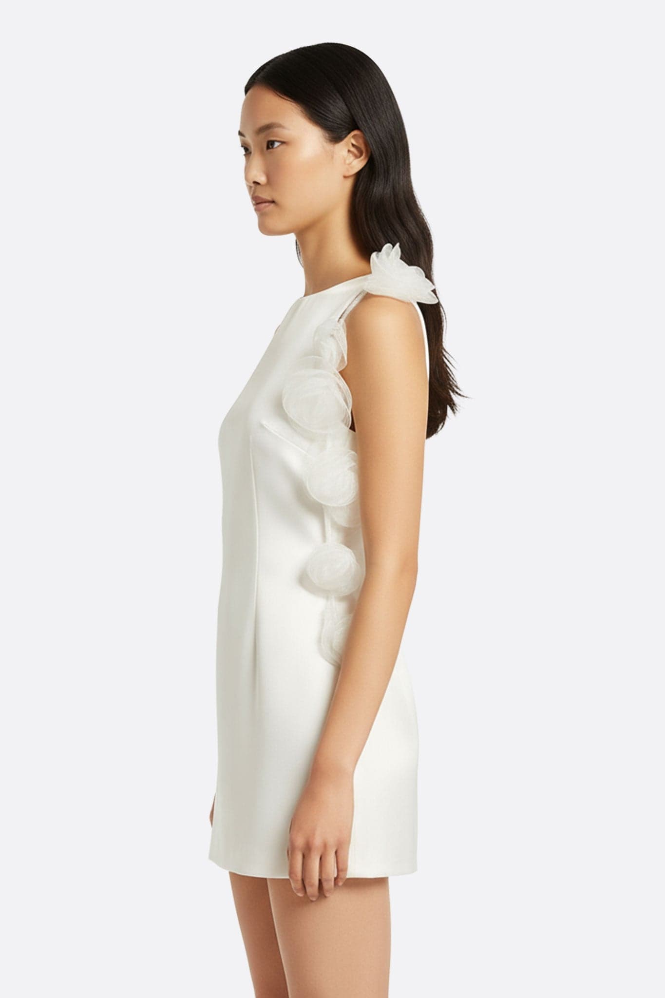 White satin dress with open back, adorned with sculptural flowers, 3/4 view ideal for an elegant and modern occasion