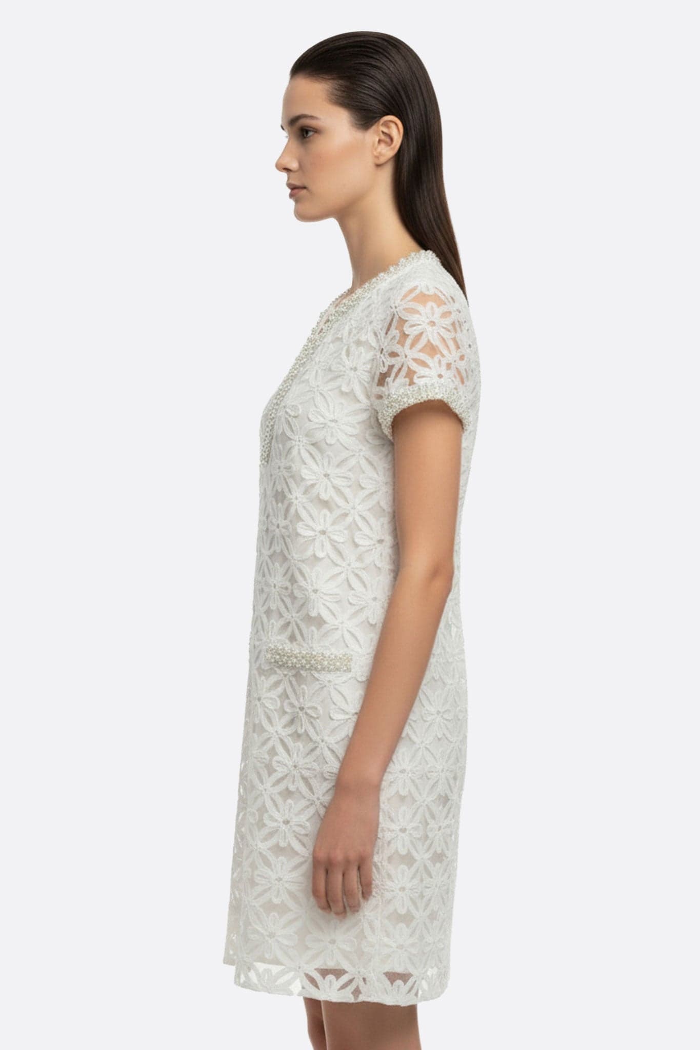 Détail rapproché d'une robe courte blanche avec broderie florale perlée, idéale pour une tenue estivale chic et raffinée.