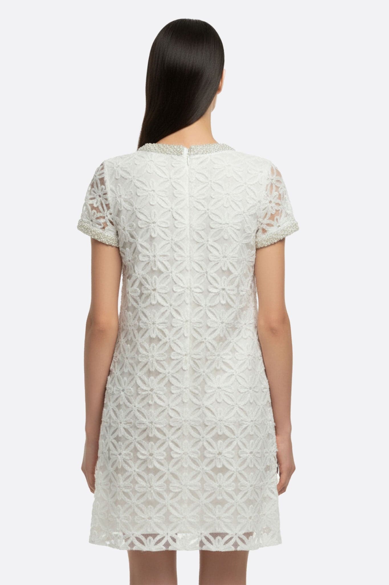 Perspective alternative sur une robe courte blanche ornée de broderie florale perlée, parfaite pour une occasion chic en...