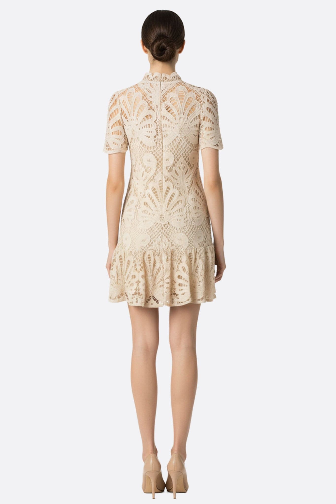 Prospettiva alternativa sull'abito corto in pizzo beige, che mette in risalto la delicatezza dei suoi eleganti motivi traforati.