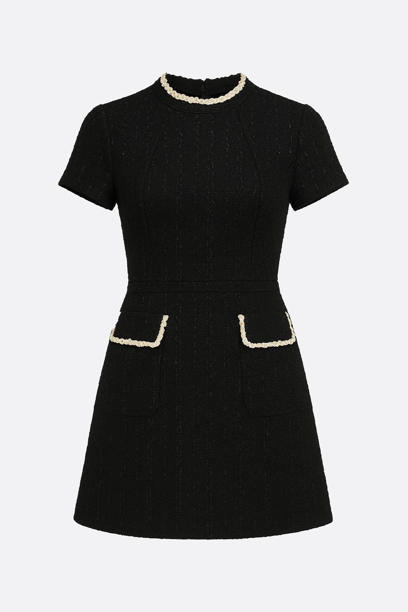 Zoom sur le col bijou doré de la robe courte en tweed noir, ajoutant une touche d'élégance à votre tenue chic.