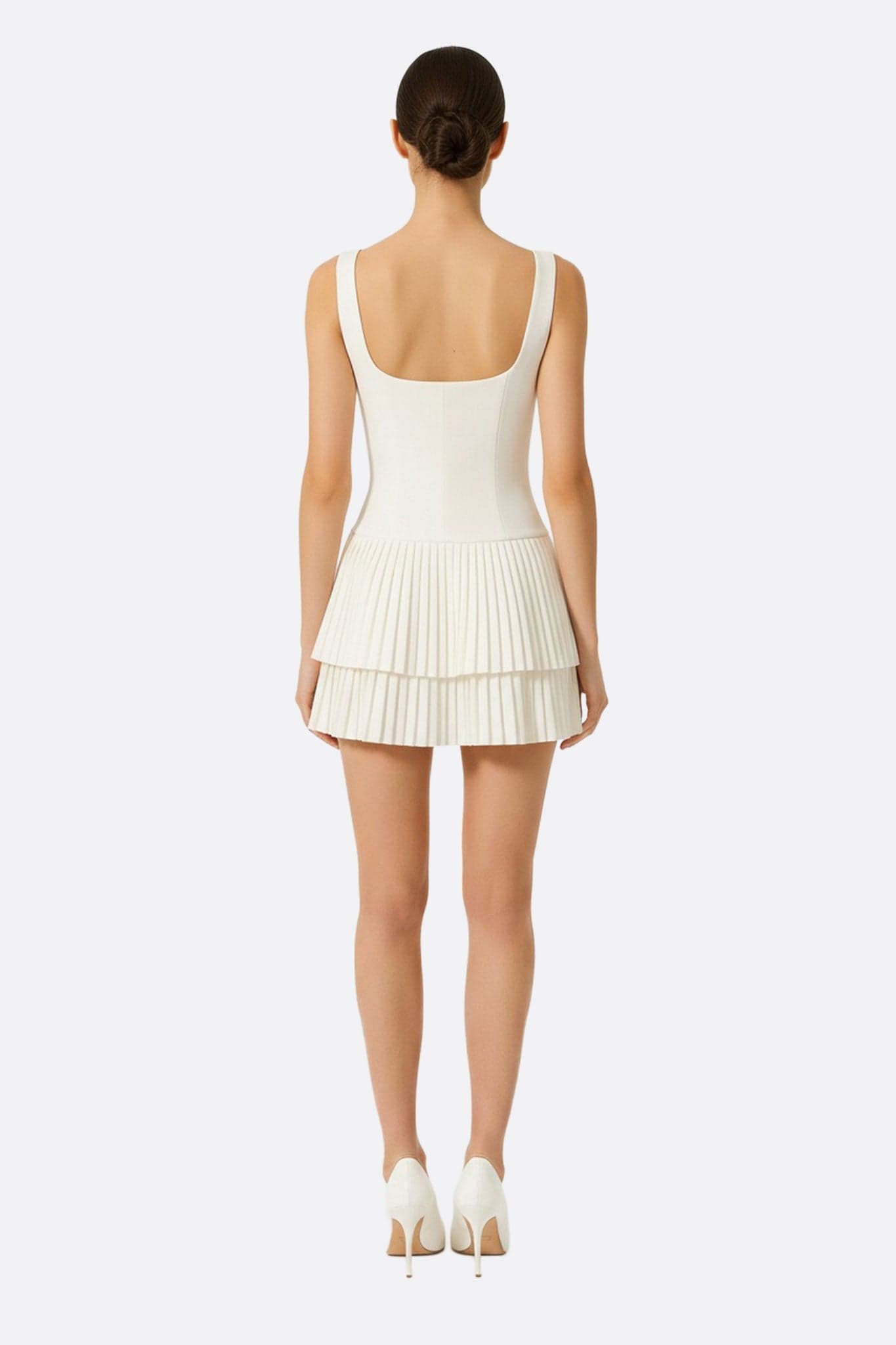 Robe blanche courte à jupe évasée, mise en valeur par un angle inédit, idéale pour un style sophistiqué au quotidien.