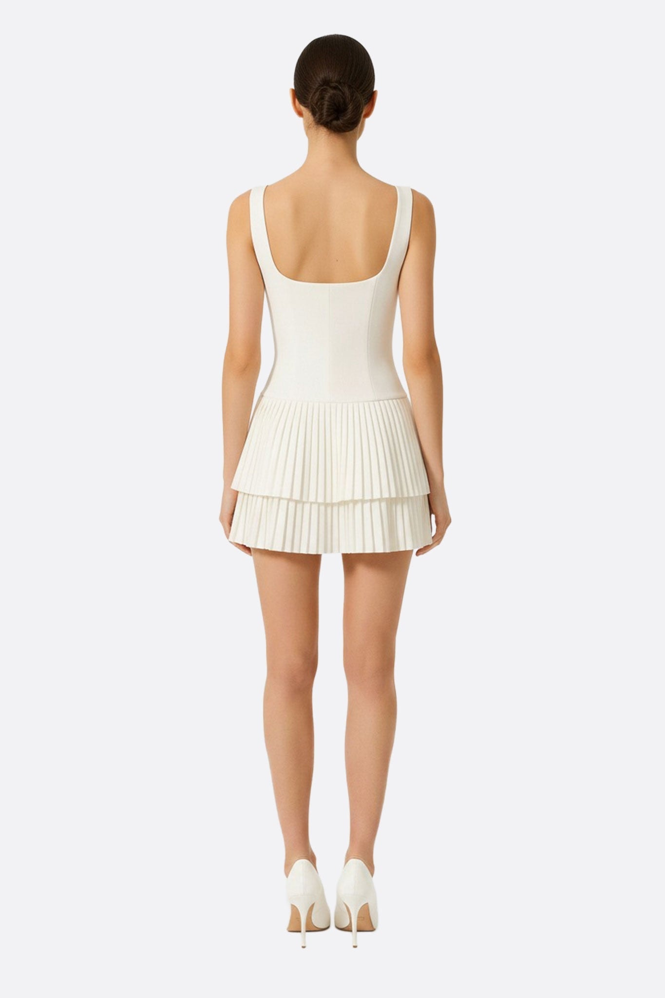 Robe blanche courte à jupe évasée, mise en valeur par un angle inédit, idéale pour un style sophistiqué au quotidien.