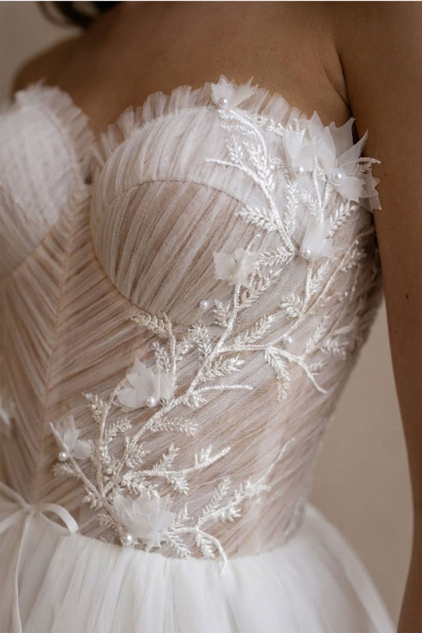 Detail des Alena Brautkleides aus weißem Tüll, betont das Bustier und den Überwurf für eine romantische Ausstrahlung.