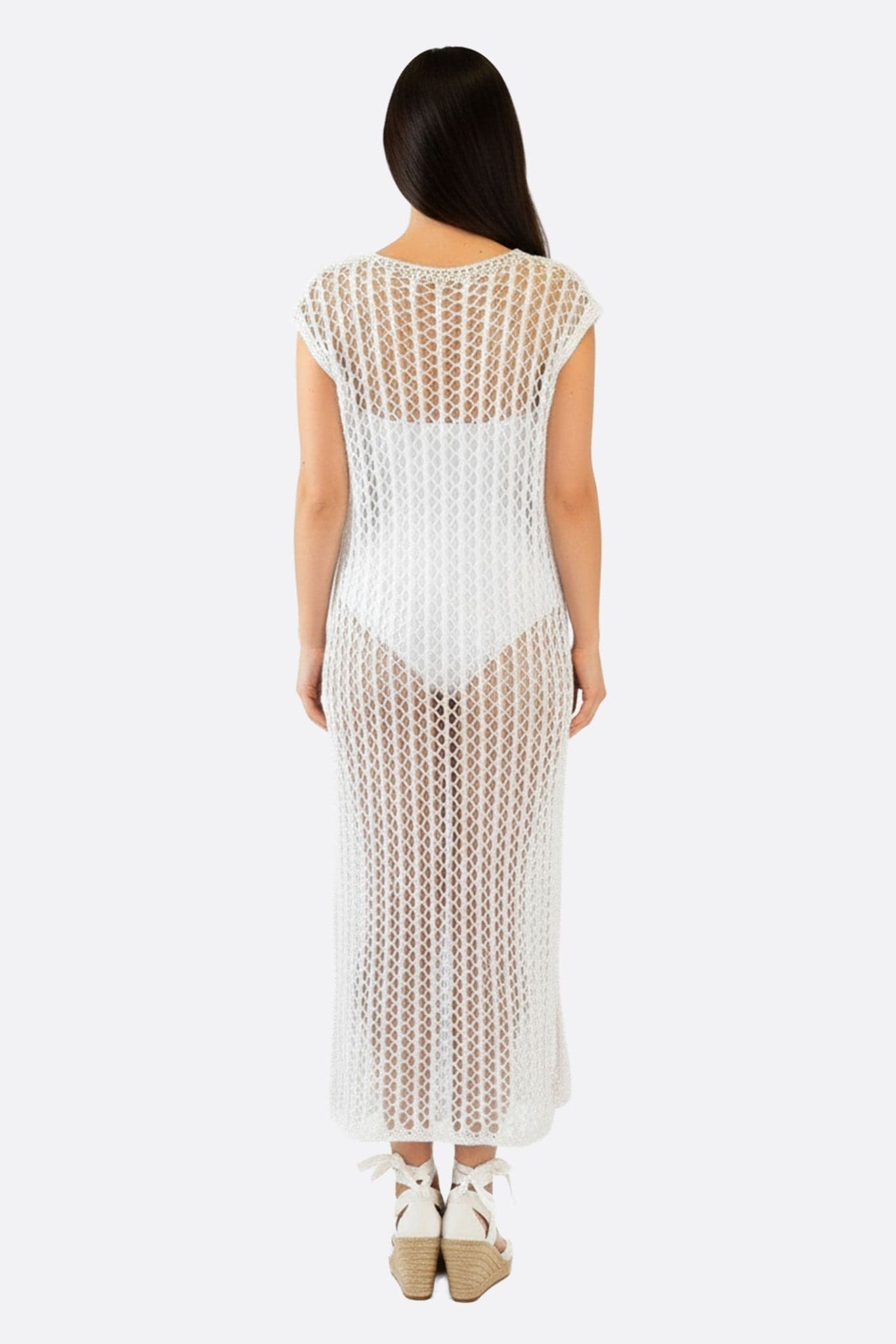 Bohemien-Strandkleid aus weißem Häkelstrick, mit offener Webart, ideal für einen sommerlichen Tag am Meer.