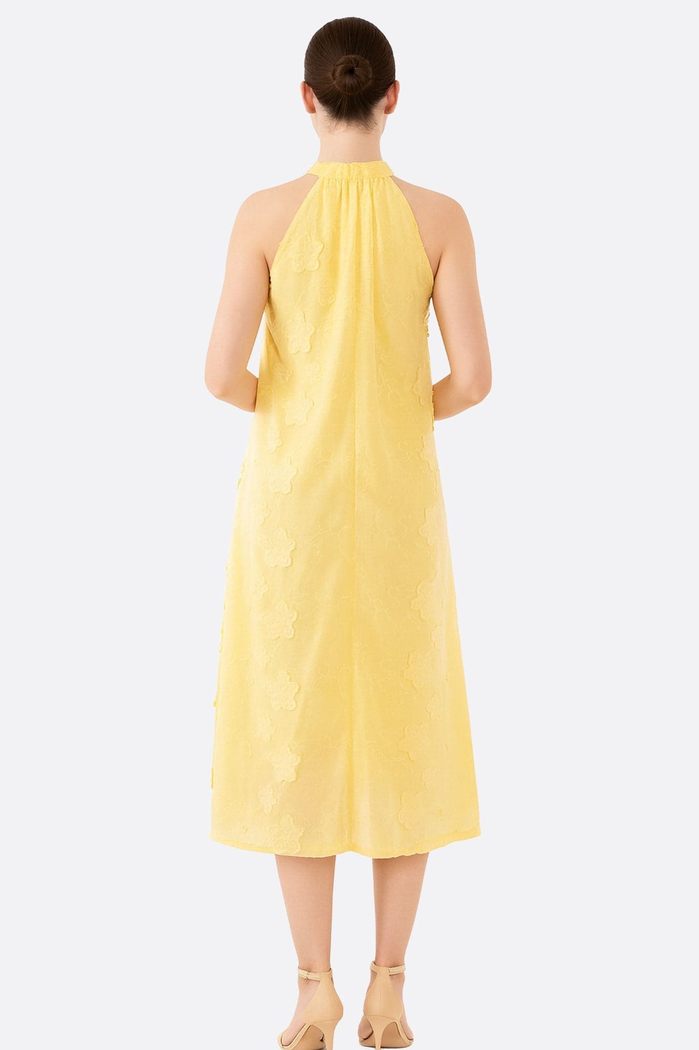 Abito fluido giallo con motivo floreale in jacquard, vista 3/4 che rivela l'elegante collo alto, perfetto per le sere d'estate